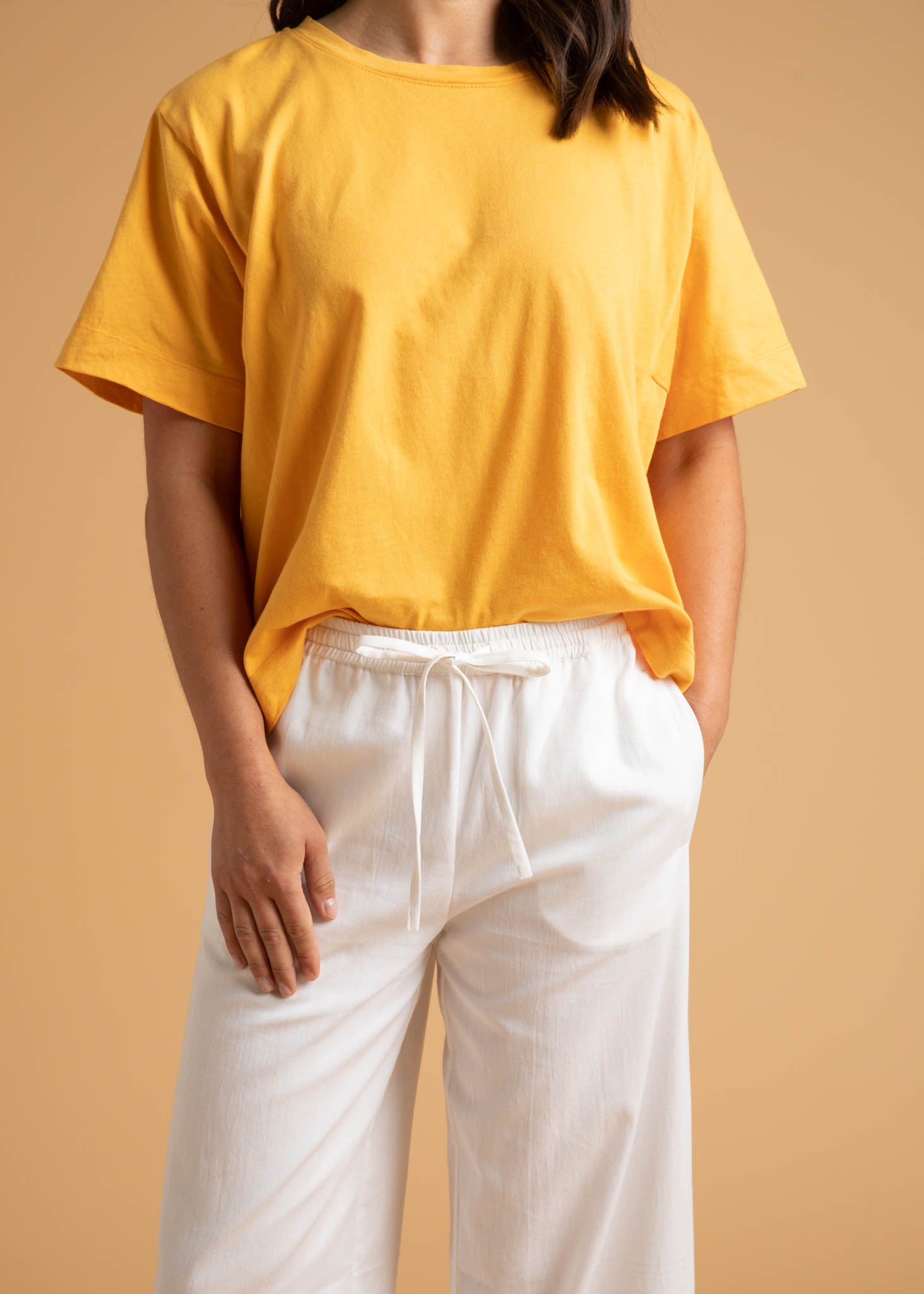 A pair of Shore Pants in Natural color, featuring a modern cropped length, relaxed fit, and elastic waist, displayed on a neutral background.