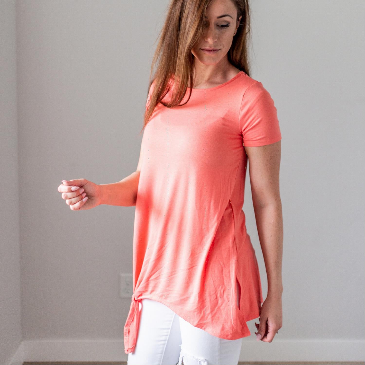 Woman in coral asymmetrical top.