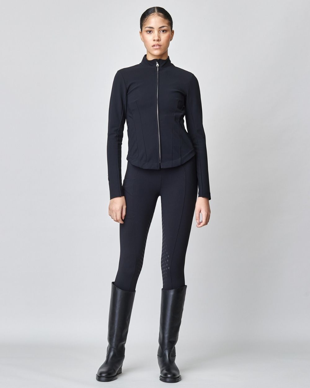 A stylish black riding jacket made from Italian jersey fiber, featuring a fitted silhouette and laser-cut edges, perfect for equestrian wear.