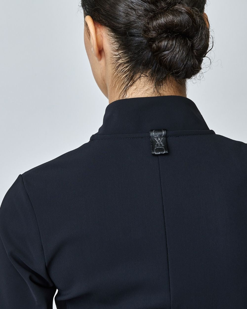 A stylish black riding jacket made from Italian jersey fiber, featuring a fitted silhouette and laser-cut edges, perfect for equestrian wear.