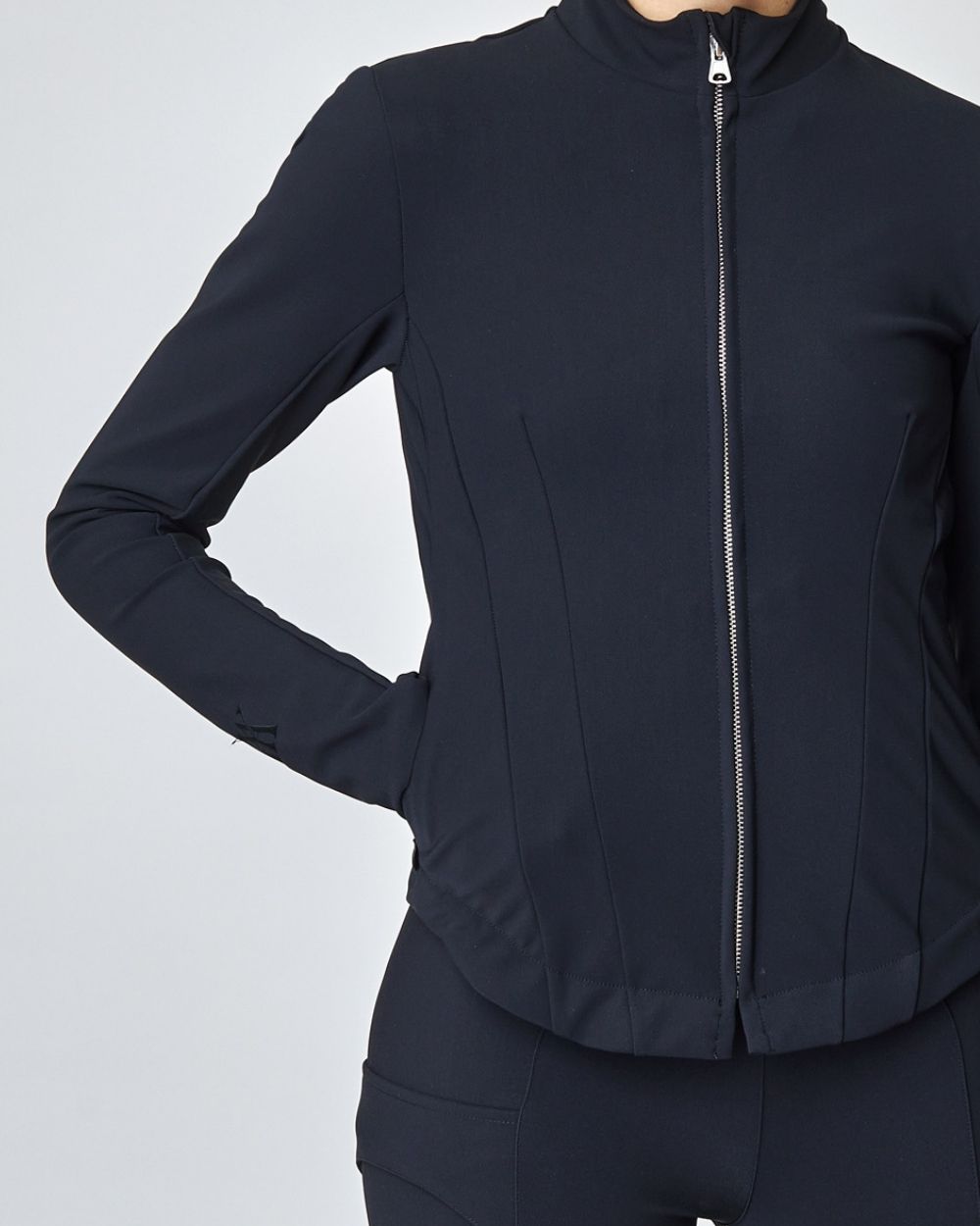 A stylish black riding jacket made from Italian jersey fiber, featuring a fitted silhouette and laser-cut edges, perfect for equestrian wear.