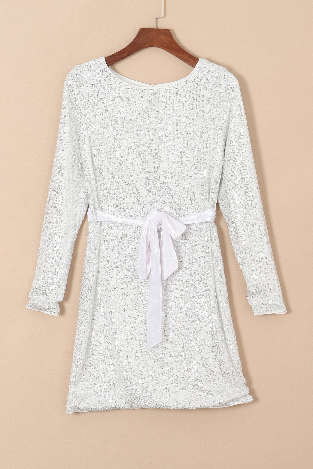 Silvery sequin long sleeve mini dress with tie waist sash, showcasing a boat neckline and elegant design.