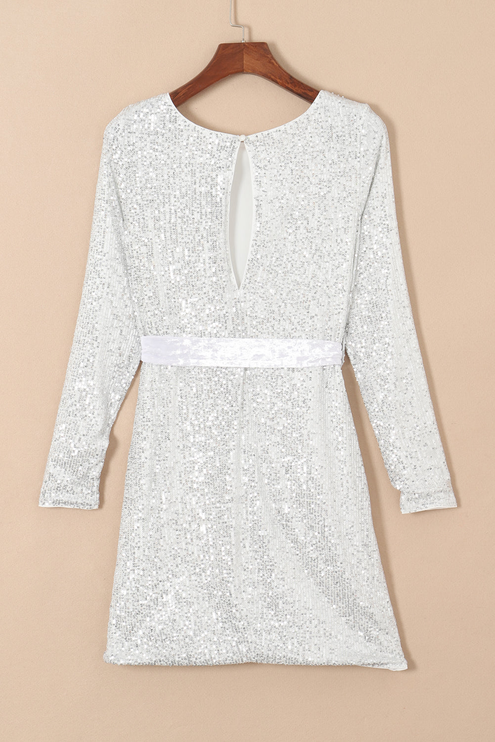 Silvery sequin long sleeve mini dress with tie waist sash, showcasing a boat neckline and elegant design.