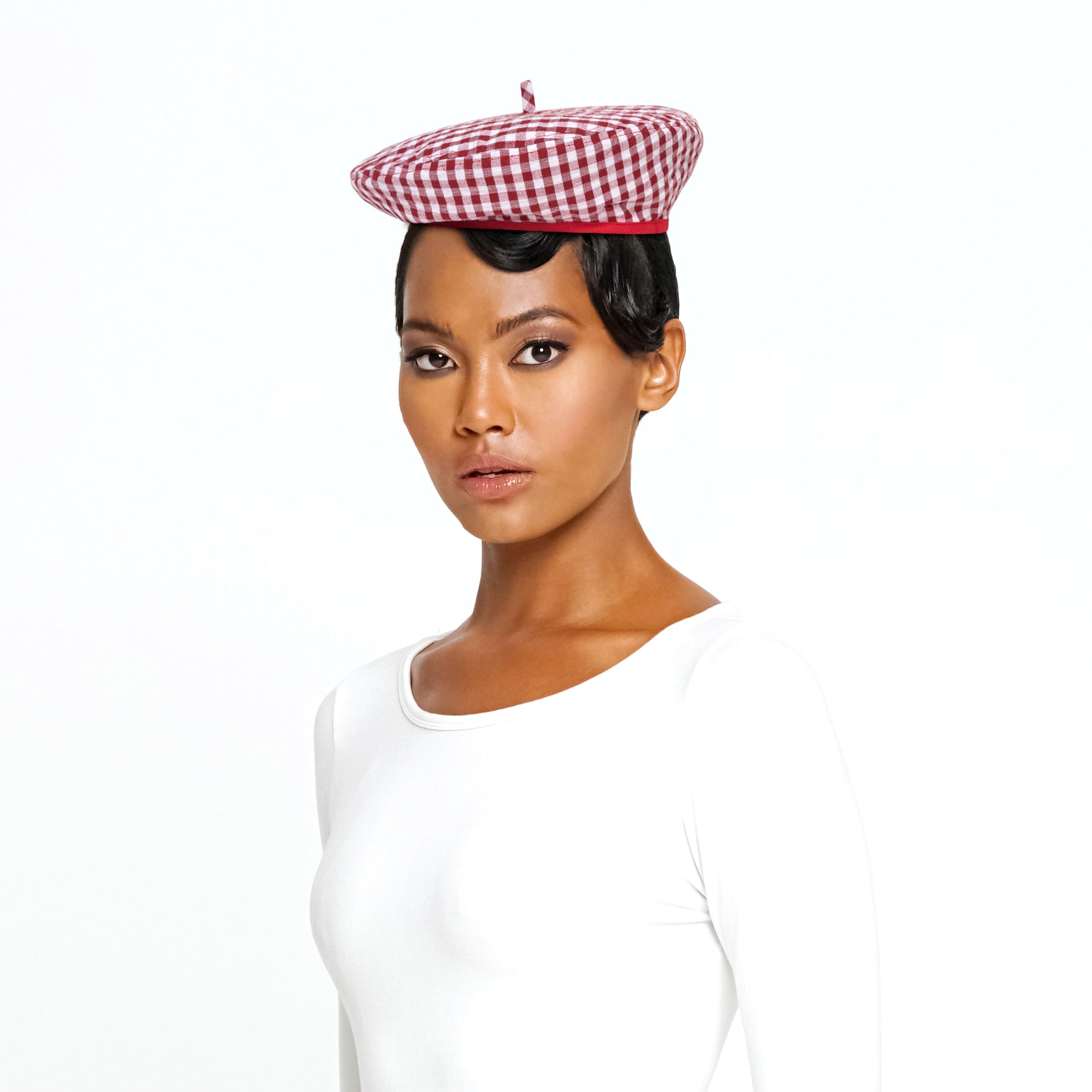 A stylish red gingham beret hat made from soft cotton with a comfortable linen lining, showcasing its eco-friendly design.