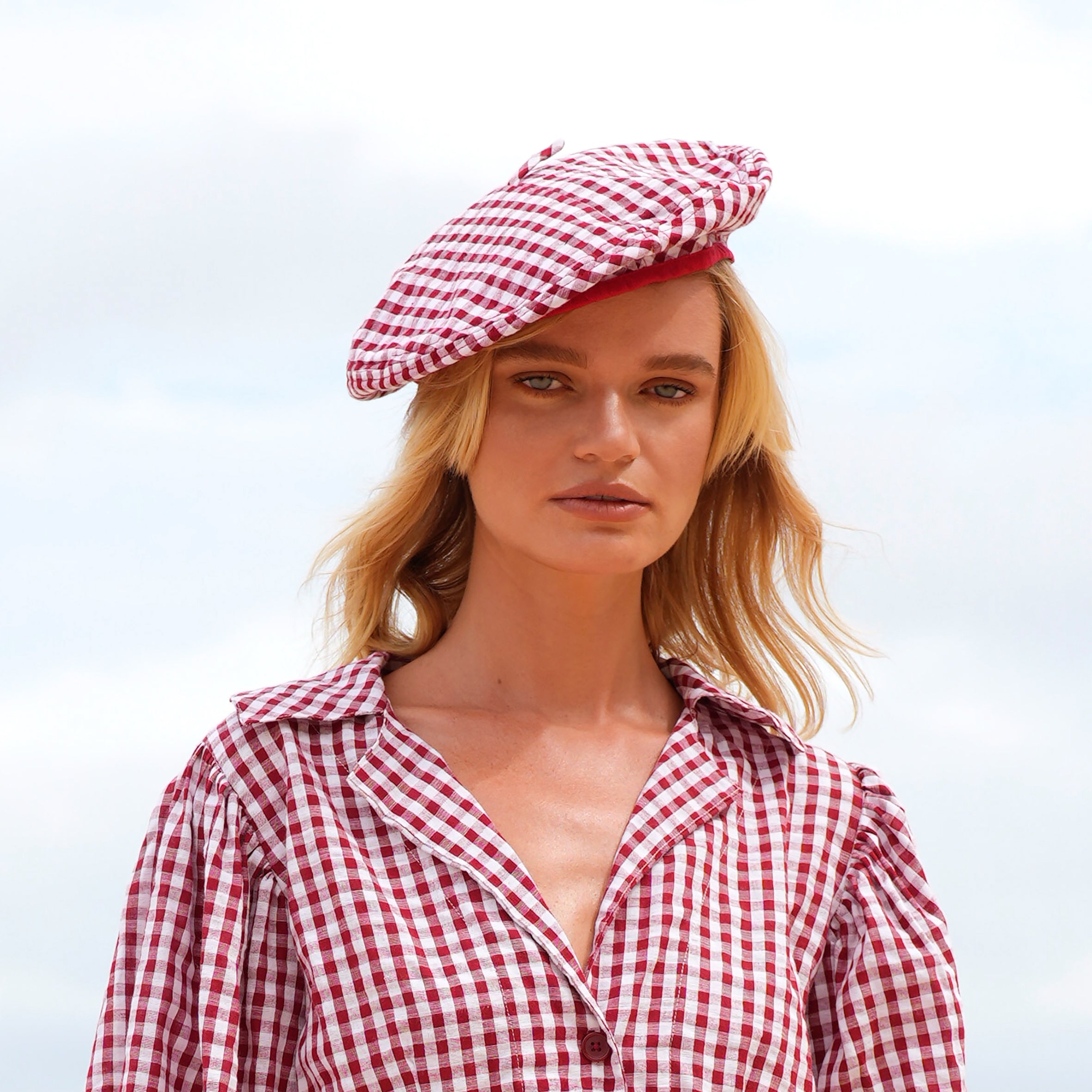 A stylish red gingham beret hat made from soft cotton with a comfortable linen lining, showcasing its eco-friendly design.