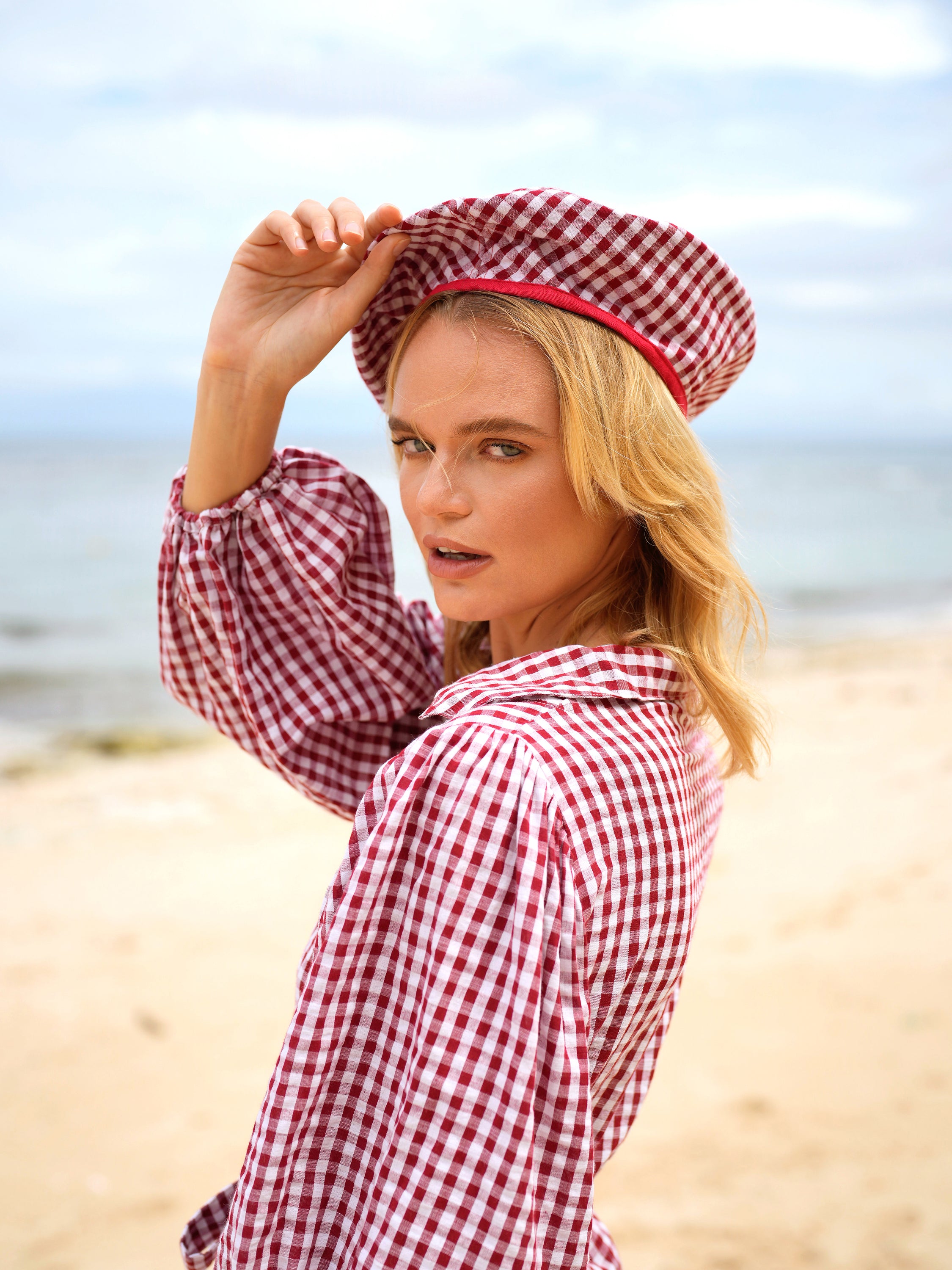 A stylish red gingham beret hat made from soft cotton with a comfortable linen lining, showcasing its eco-friendly design.