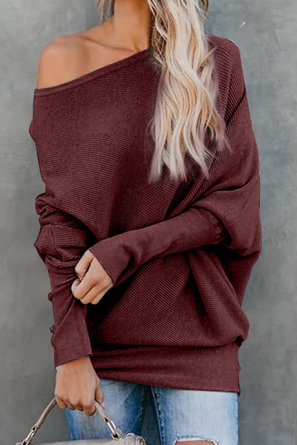 A stylish slouchy one shoulder dolman sleeves ribbed sweater in a solid color, showcasing its relaxed fit and elegant design.