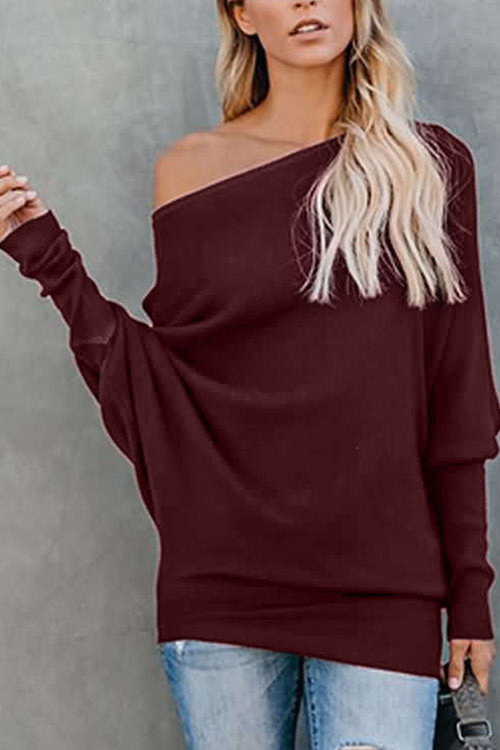 A stylish slouchy one shoulder dolman sleeves ribbed sweater in a solid color, showcasing its relaxed fit and elegant design.