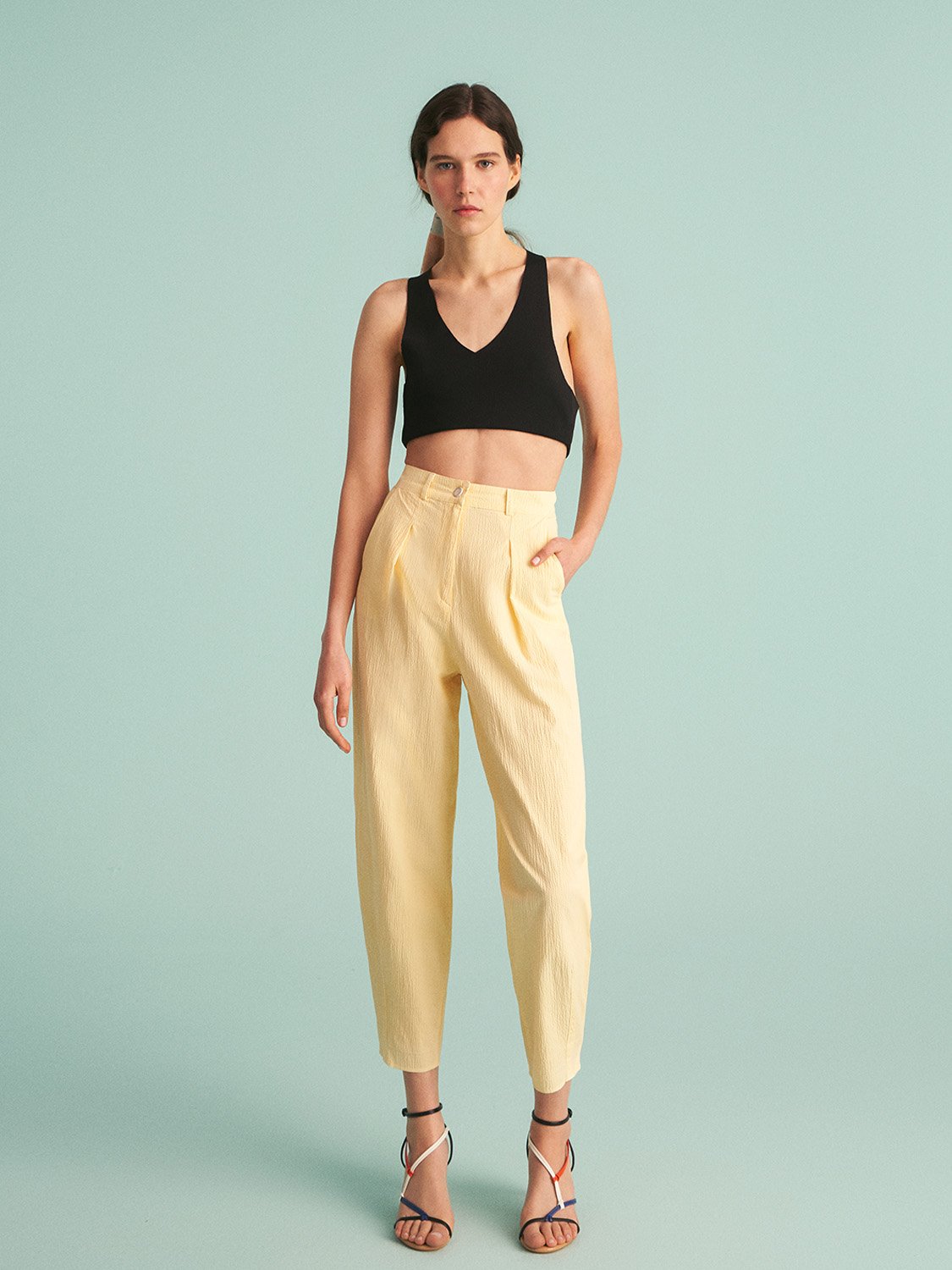 A pair of stylish high-waisted slouchy pants with darts, featuring side pockets and a front zip closure, showcasing a comfortable and chic design.