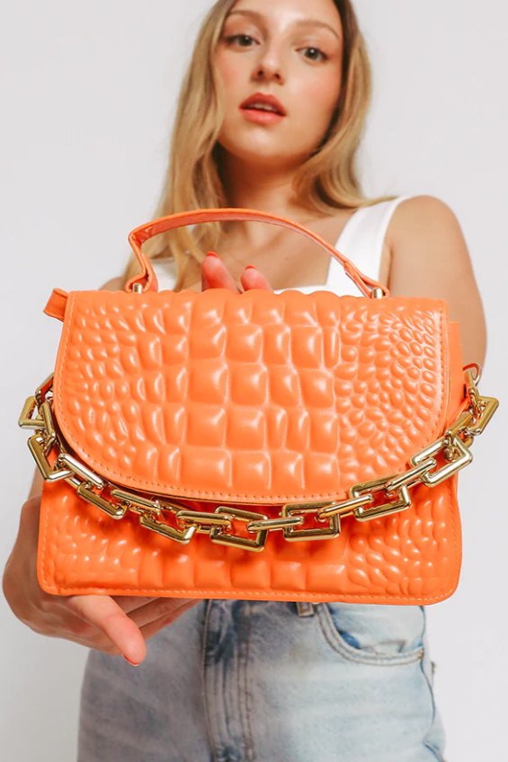 Elegant small orange bag with decorative chain made of high-quality faux leather.