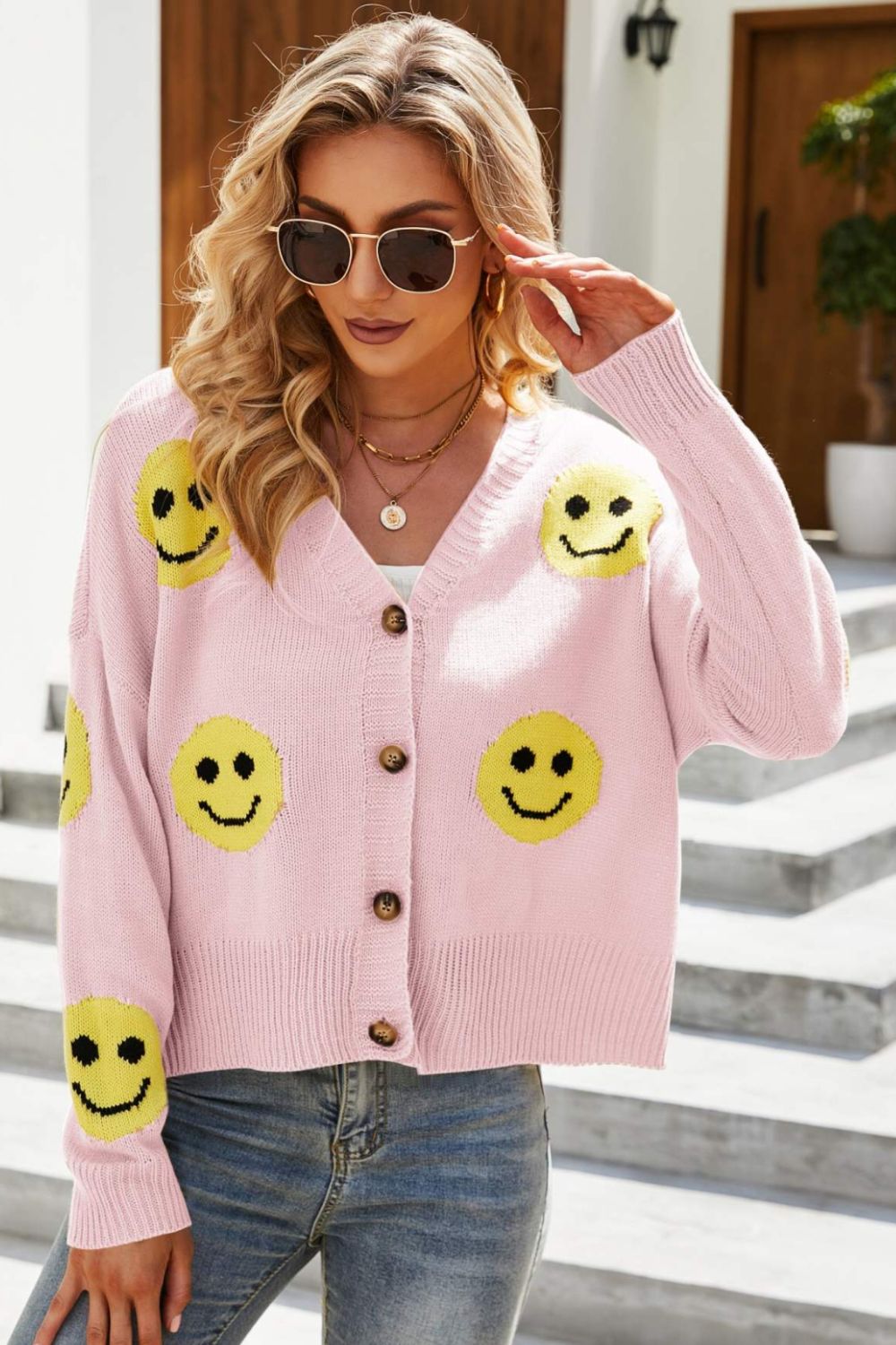 Smiley Face Ribbed Trim V-Neck Cardigan displayed outdoors, featuring a playful smiley face pattern and ribbed trim.