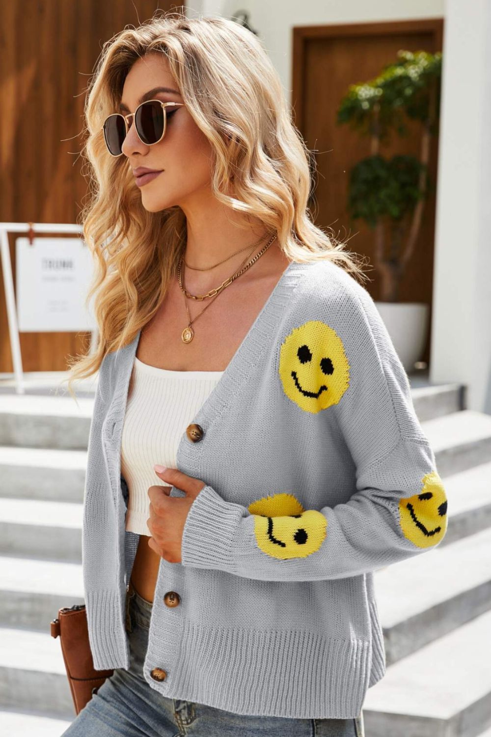 Smiley Face Ribbed Trim V-Neck Cardigan displayed outdoors, featuring a playful smiley face pattern and ribbed trim.