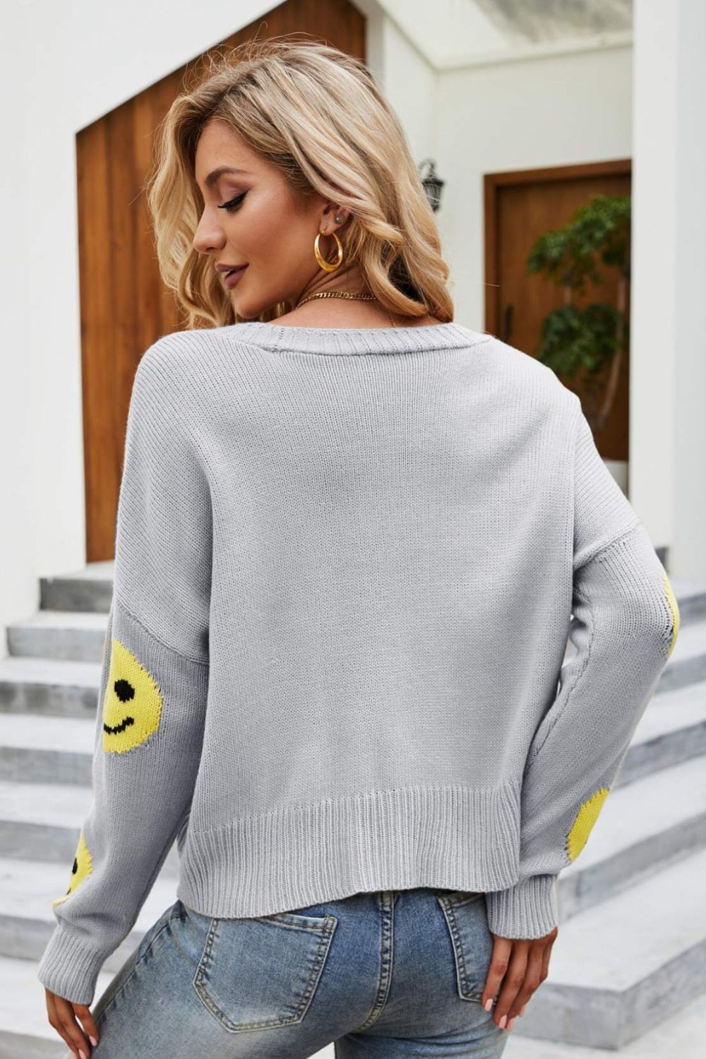 Smiley Face Ribbed Trim V-Neck Cardigan displayed outdoors, featuring a playful smiley face pattern and ribbed trim.