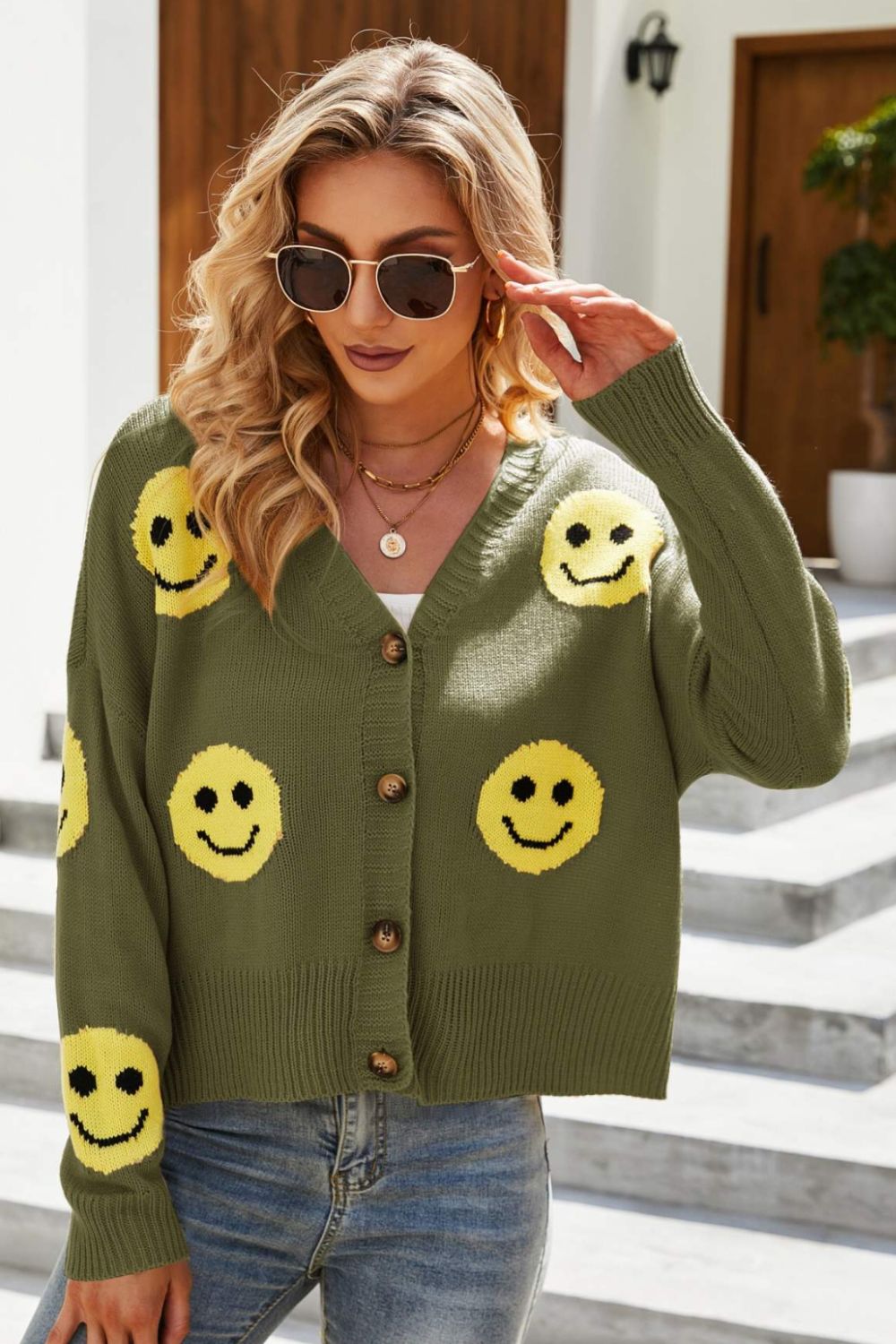 Smiley Face Ribbed Trim V-Neck Cardigan displayed outdoors, featuring a playful smiley face pattern and ribbed trim.