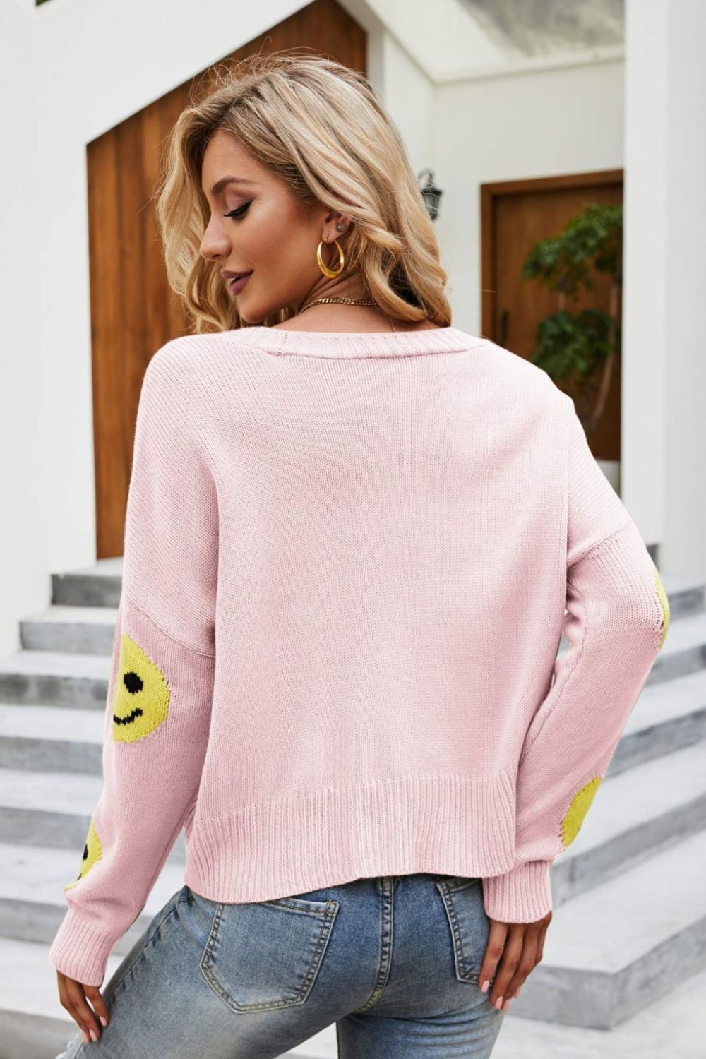 Smiley Face Ribbed Trim V-Neck Cardigan displayed outdoors, featuring a playful smiley face pattern and ribbed trim.