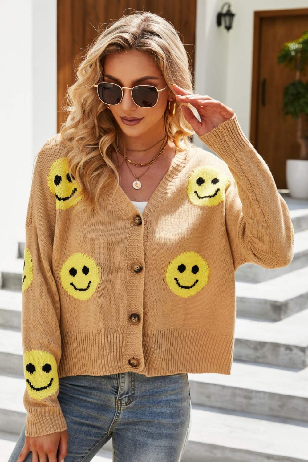 Smiley Face Ribbed Trim V-Neck Cardigan displayed outdoors, featuring a playful smiley face pattern and ribbed trim.