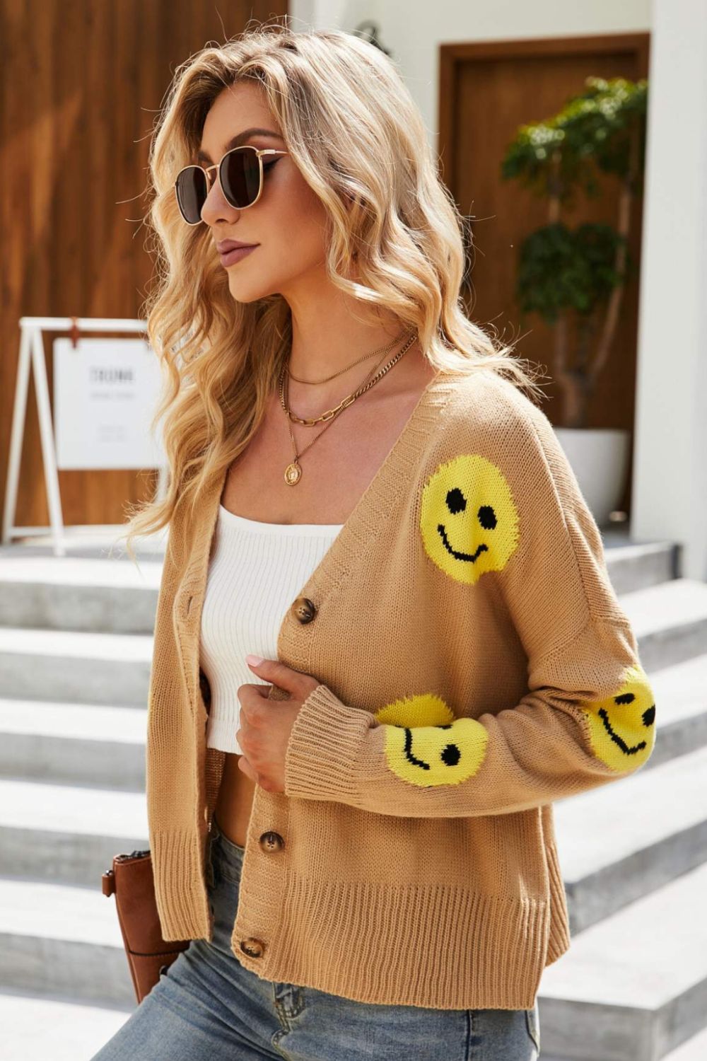 Smiley Face Ribbed Trim V-Neck Cardigan displayed outdoors, featuring a playful smiley face pattern and ribbed trim.