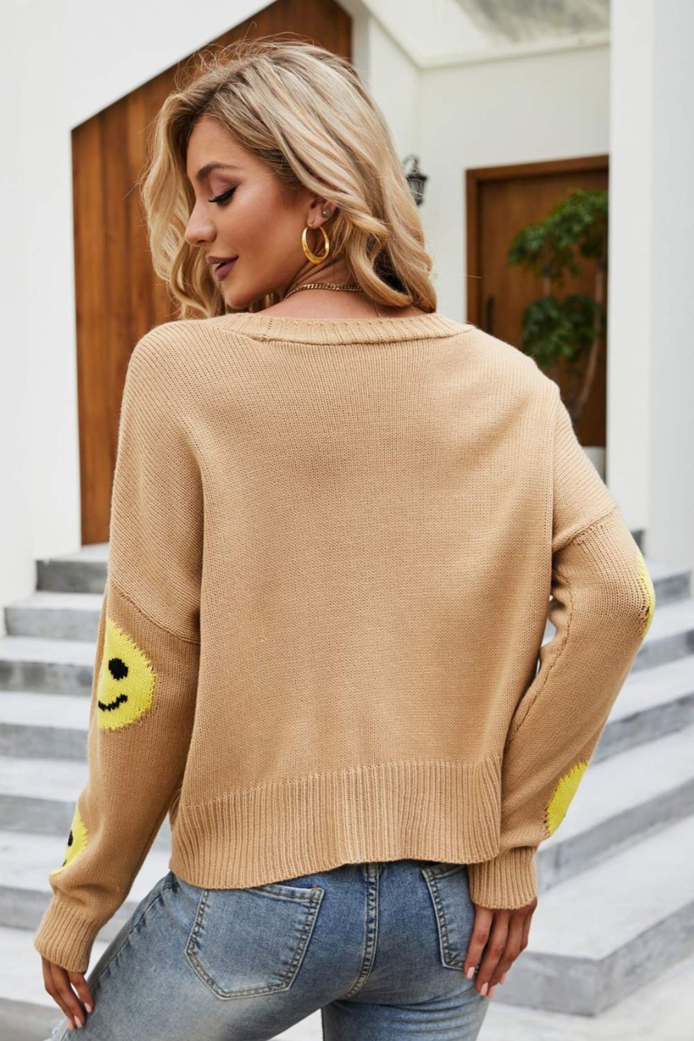 Smiley Face Ribbed Trim V-Neck Cardigan displayed outdoors, featuring a playful smiley face pattern and ribbed trim.