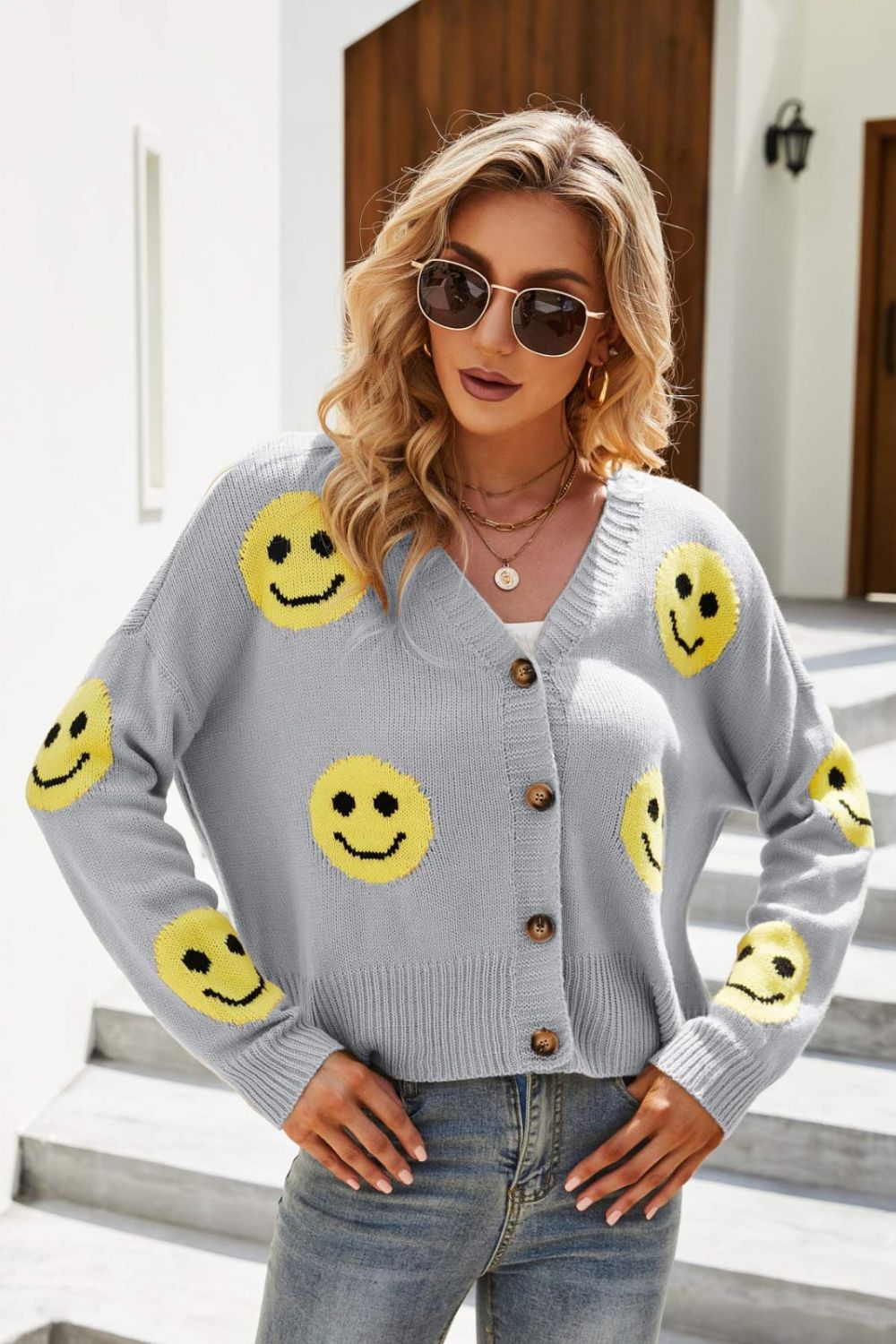 Smiley Face Ribbed Trim V-Neck Cardigan displayed outdoors, featuring a playful smiley face pattern and ribbed trim.