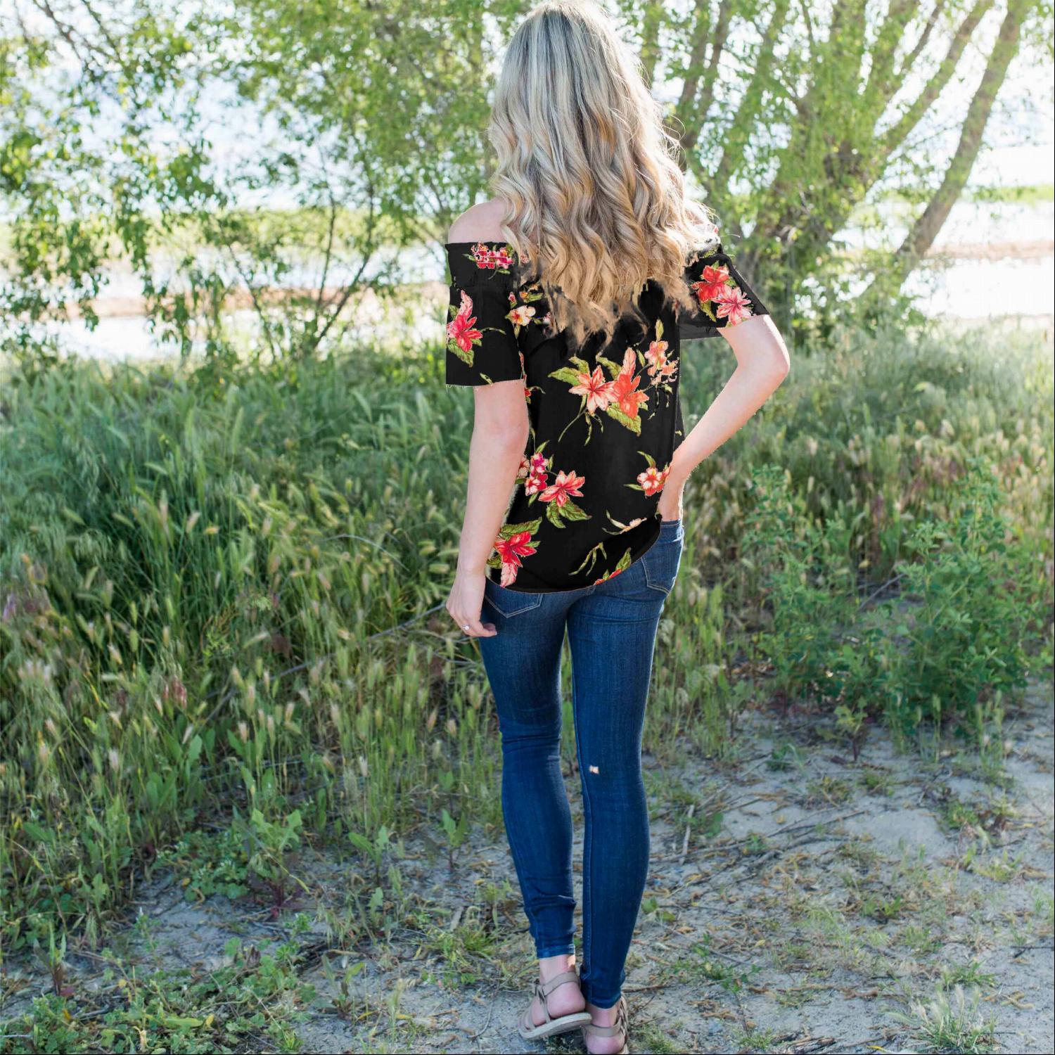 A stylish woman wearing a Smocked Floral Print Off Shoulder Top, showcasing its vibrant floral design and off-shoulder neckline.