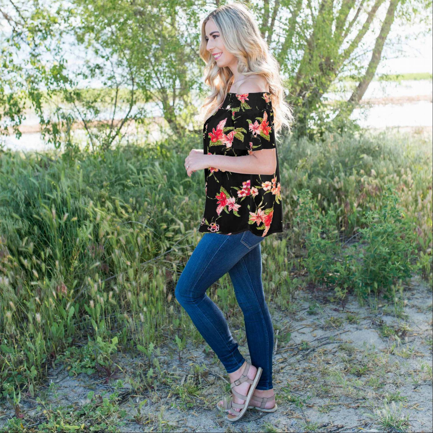 A stylish woman wearing a Smocked Floral Print Off Shoulder Top, showcasing its vibrant floral design and off-shoulder neckline.