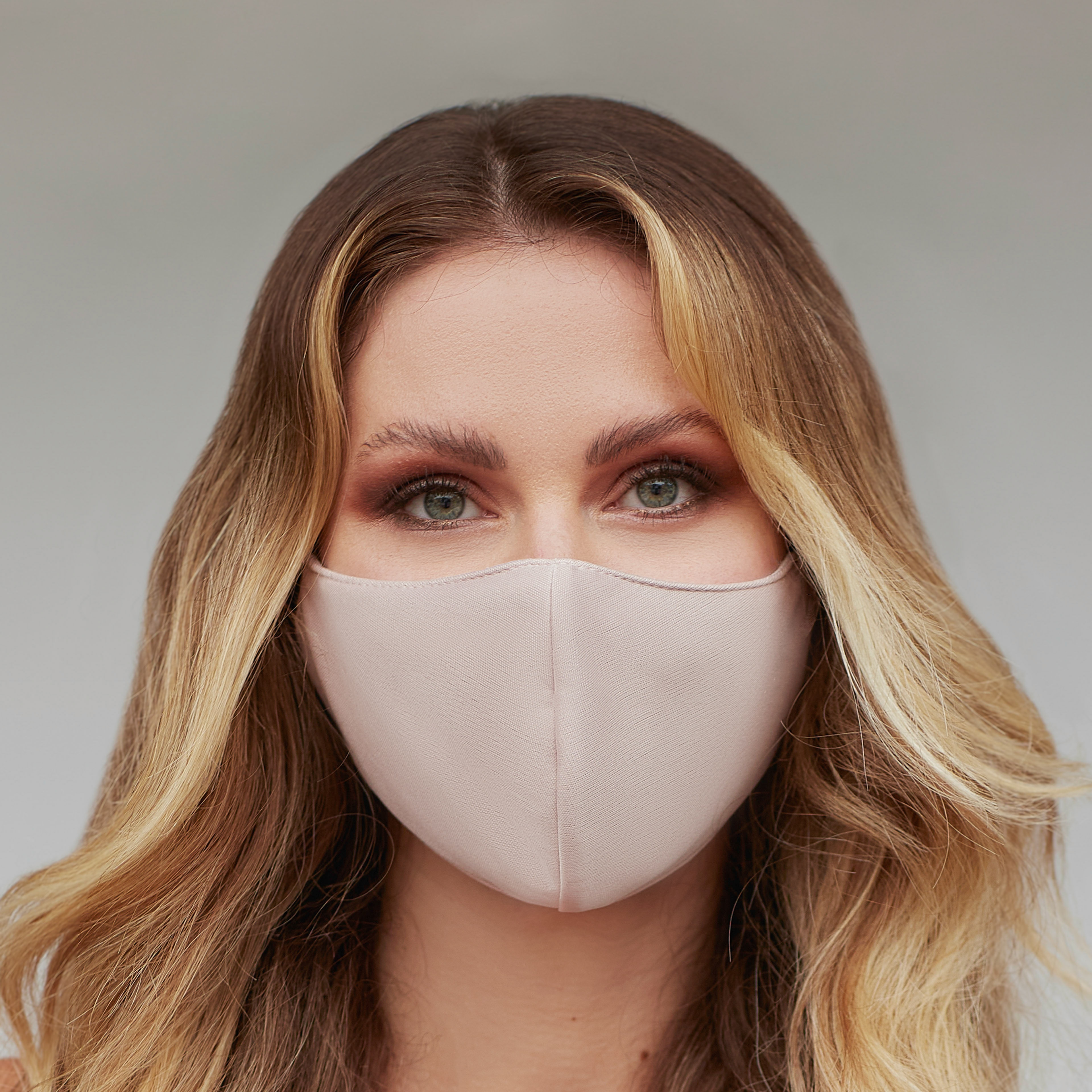 Solid tan face mask displayed on a neutral background, showcasing its fabric texture and design.