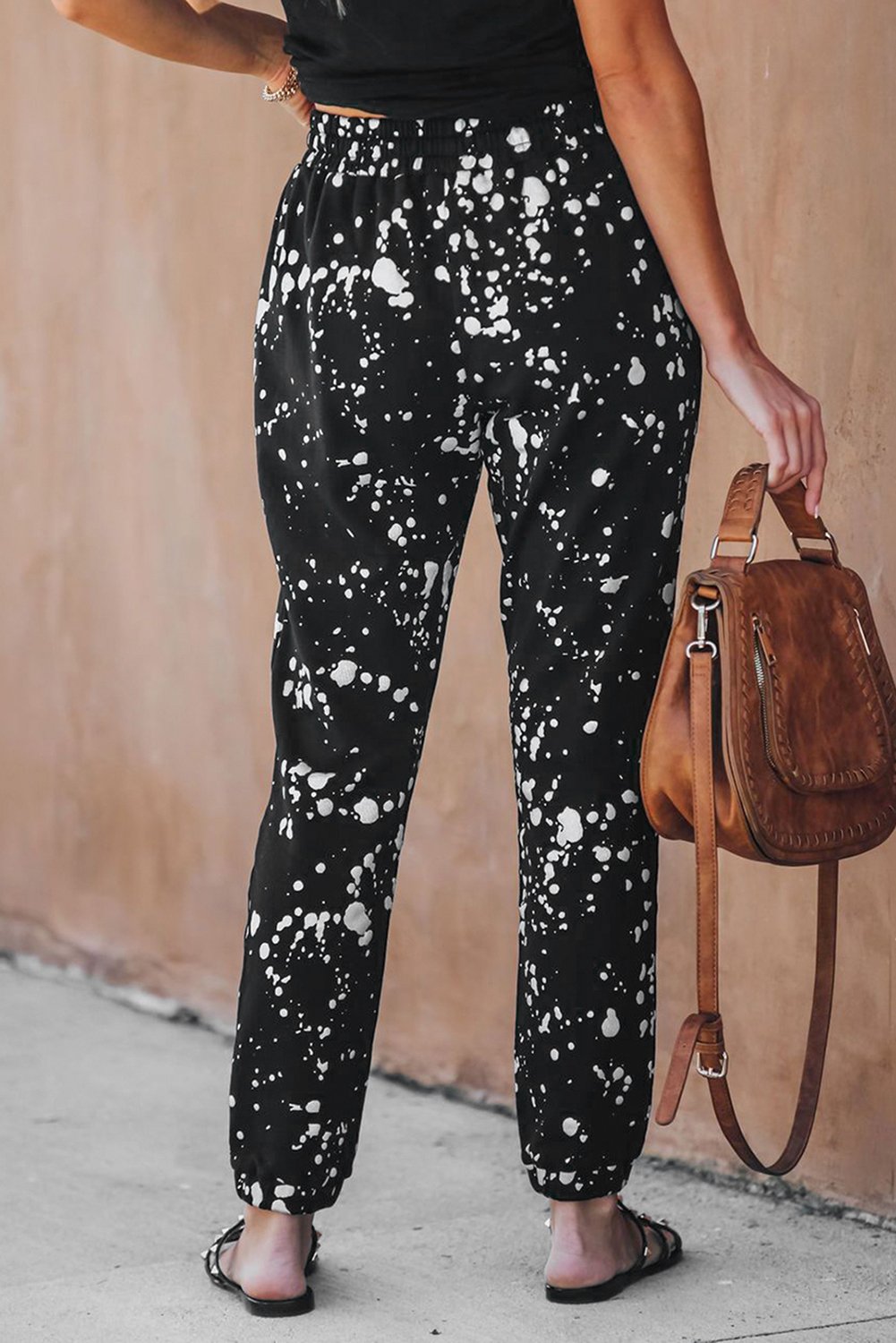 A pair of stylish Splatter Cotton Pocketed Joggers featuring a black base with metallic chrome splatter print, showcasing unfinished side pockets and a drawstring waist.