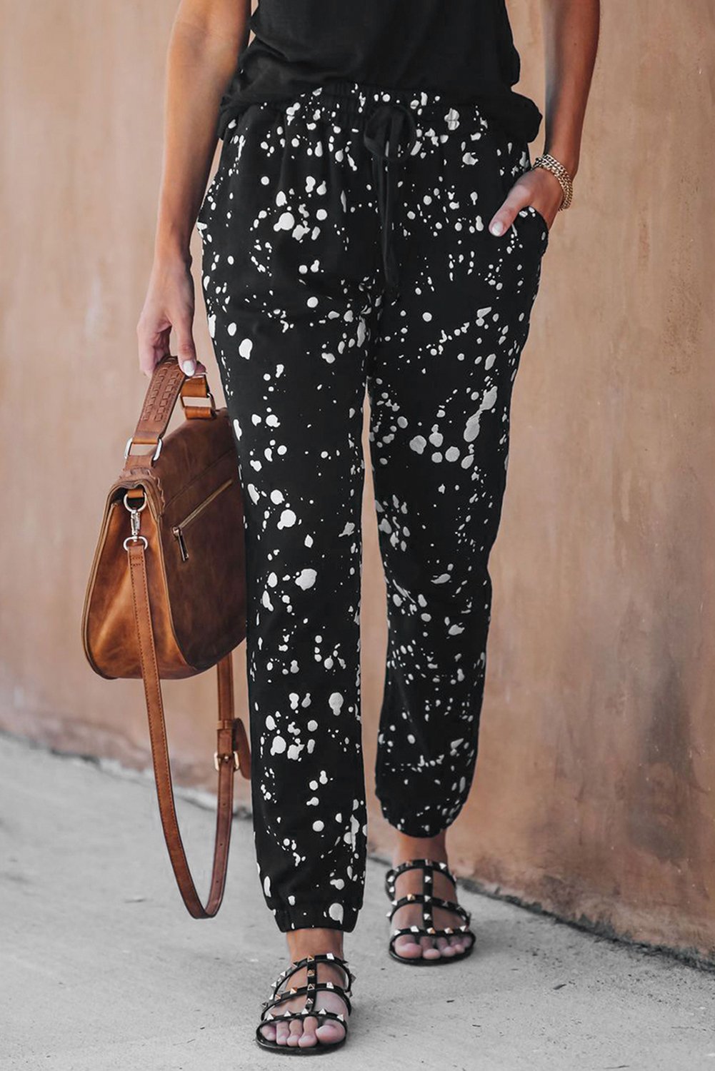 A pair of stylish Splatter Cotton Pocketed Joggers featuring a black base with metallic chrome splatter print, showcasing unfinished side pockets and a drawstring waist.