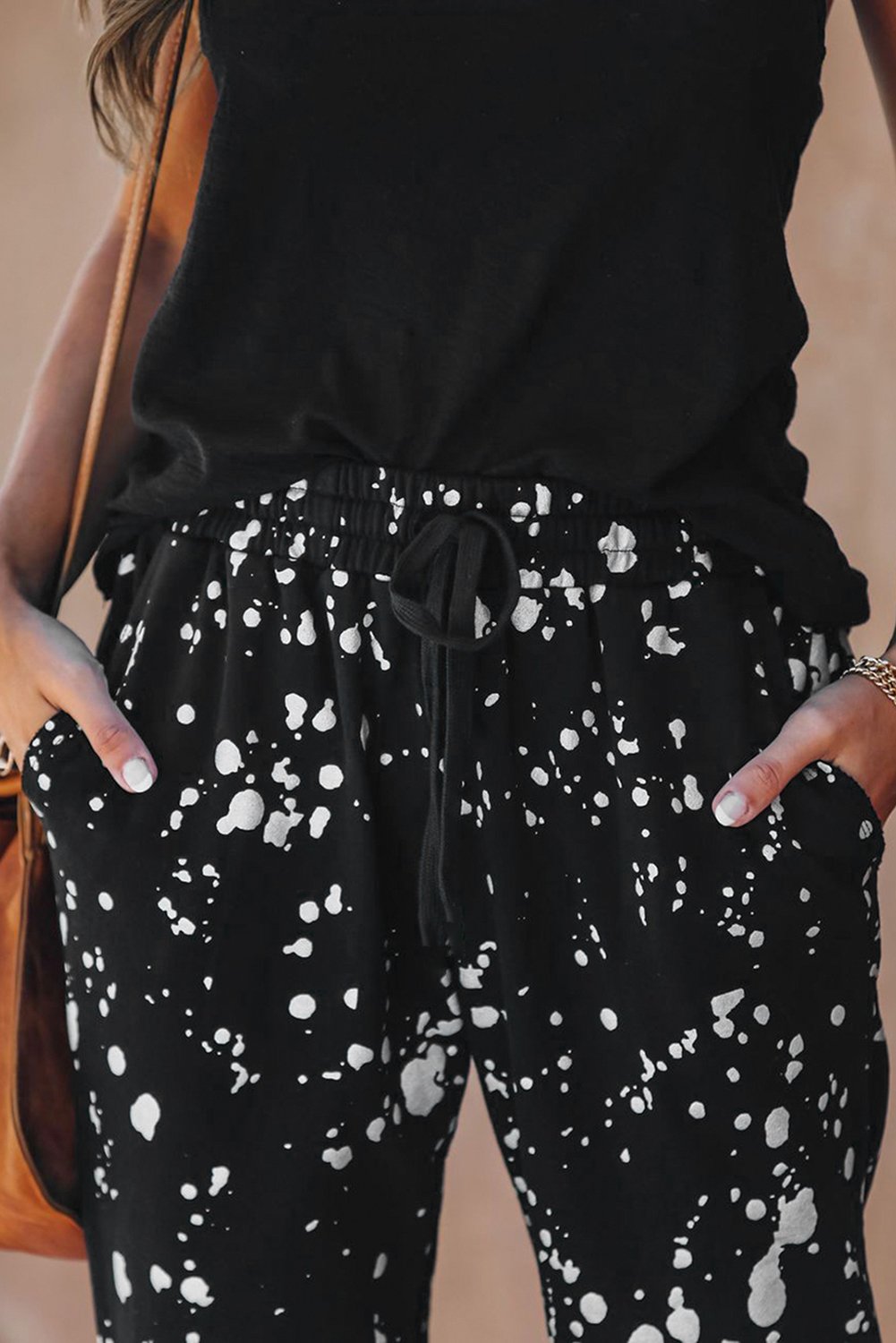 A pair of stylish Splatter Cotton Pocketed Joggers featuring a black base with metallic chrome splatter print, showcasing unfinished side pockets and a drawstring waist.