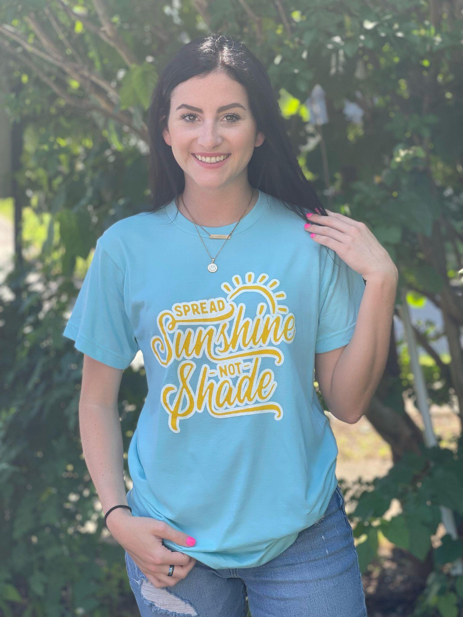 A vibrant unisex t-shirt with the phrase 'Spread Sunshine Not Shade' printed in colorful letters, showcasing a soft fabric and true-to-size fit.