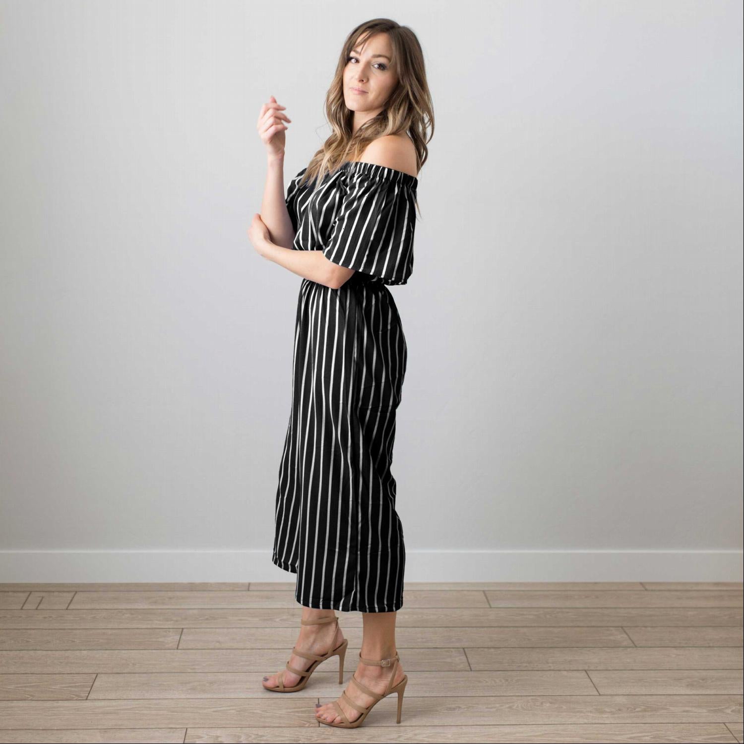 A stylish striped elbow sleeved woven jumpsuit featuring an off-the-shoulder neckline and a gaucho fit, perfect for spring and summer.