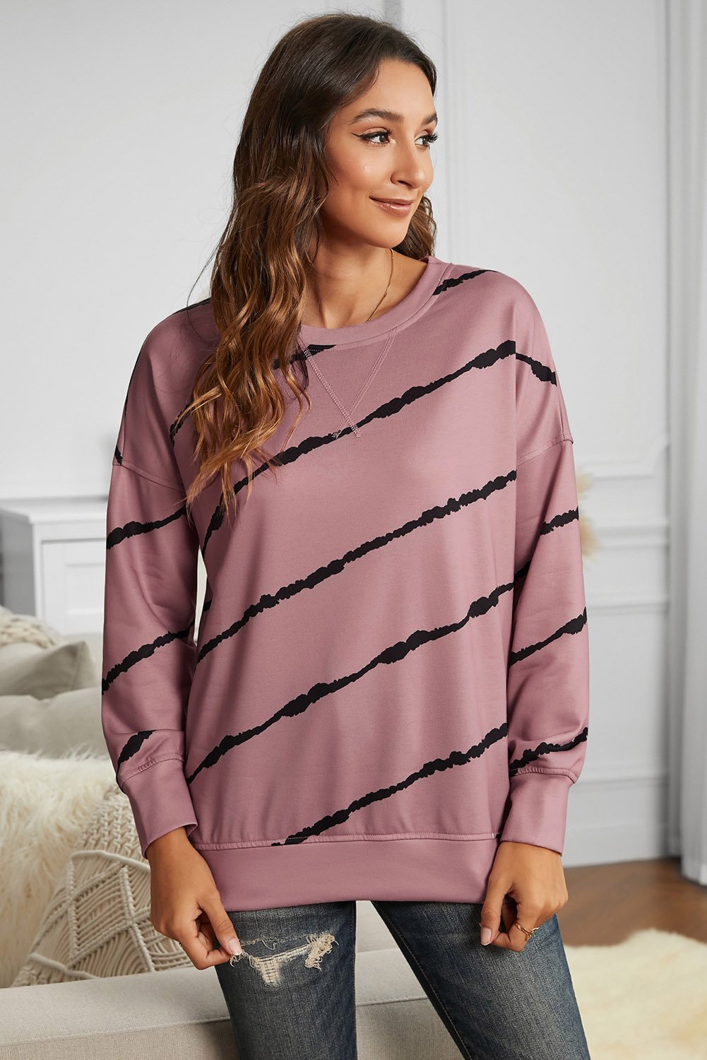 A stylish pink sweatshirt featuring a striped tie-dye print and slits on the sides, perfect for casual wear.