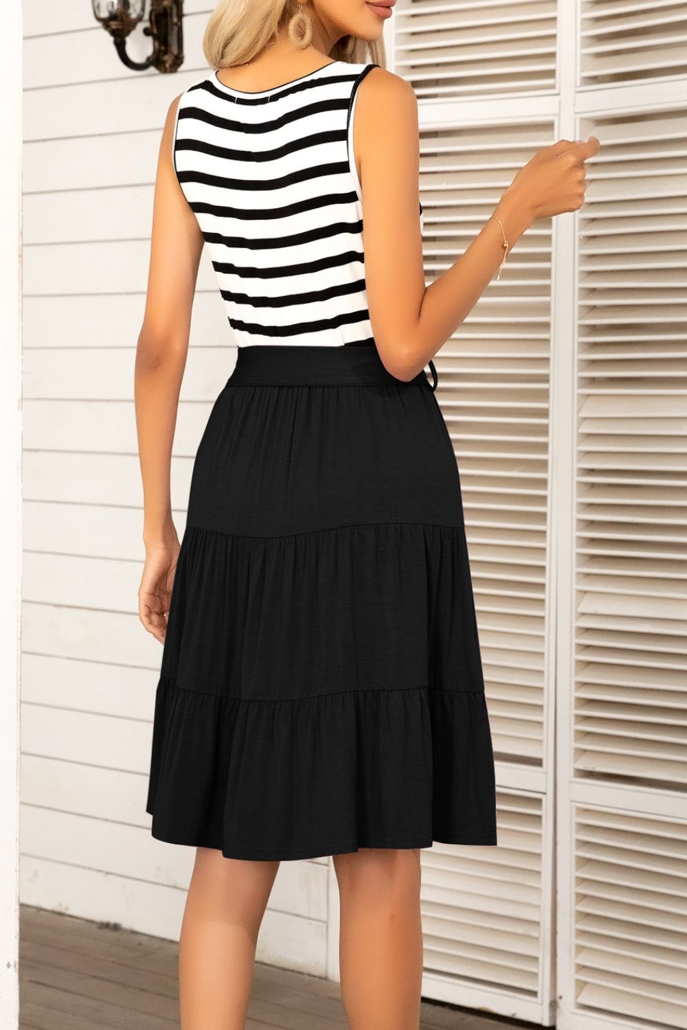 A stylish striped tie-waist sleeveless tiered dress featuring a round neckline and knee-length A-line hem, perfect for summer outings.