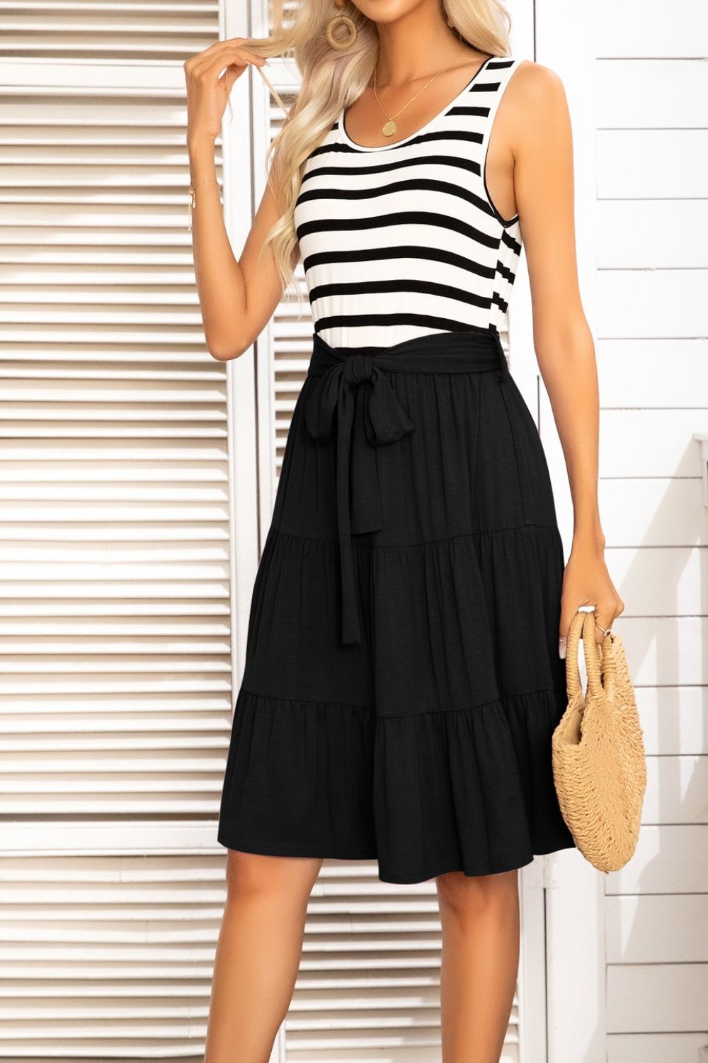 A stylish striped tie-waist sleeveless tiered dress featuring a round neckline and knee-length A-line hem, perfect for summer outings.