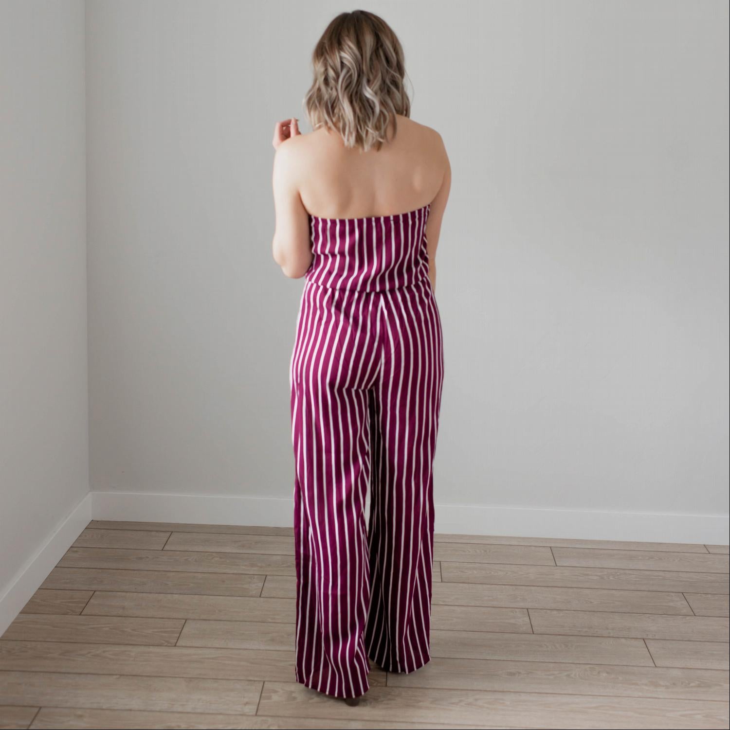 A stylish striped tube jumpsuit featuring a tube top neckline, vertical stripes, and a modest flare leg, perfect for various occasions.