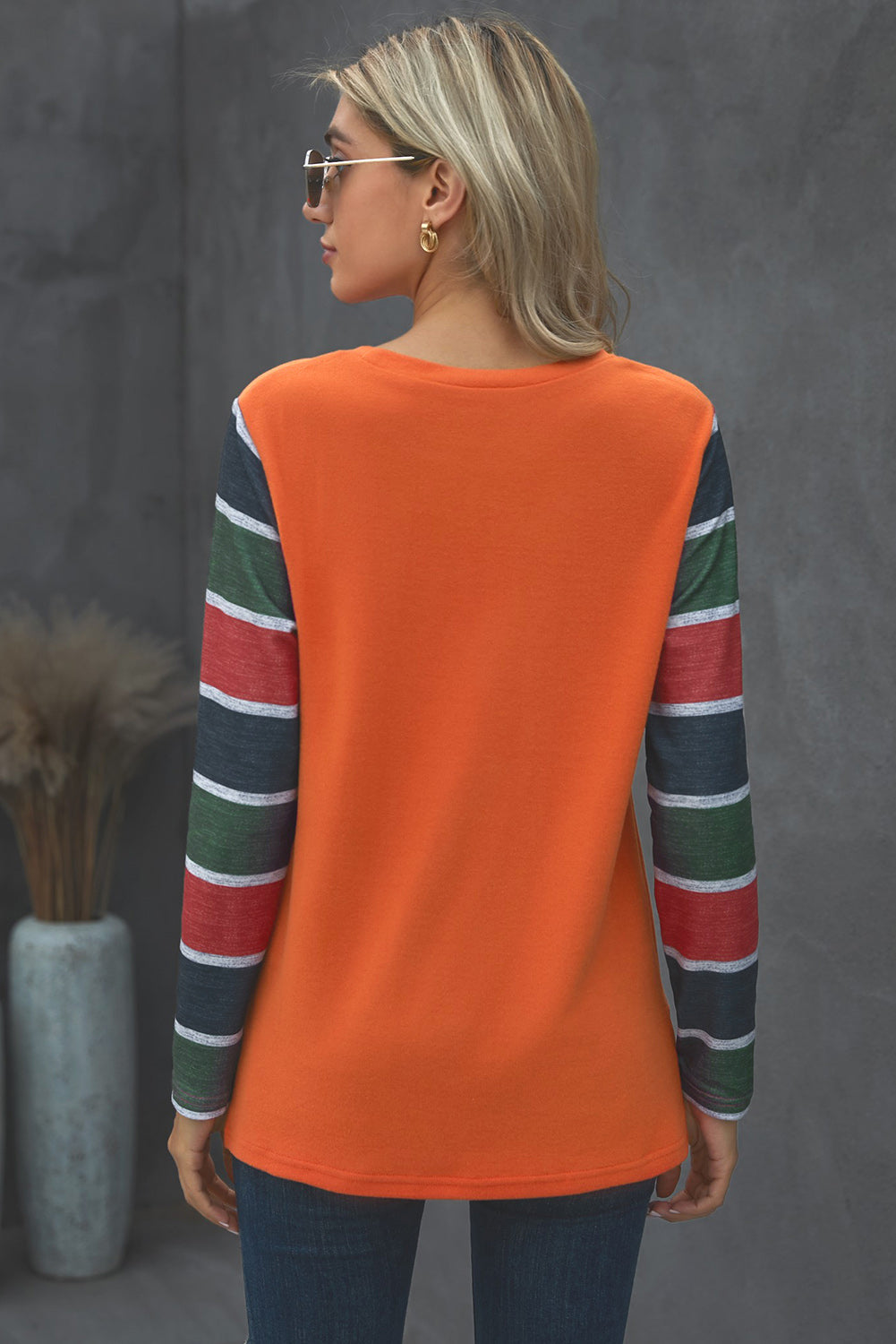 A stylish striped long sleeve top featuring a twist front design and a sparkling sequin pocket, displayed in an outdoor flat lay.