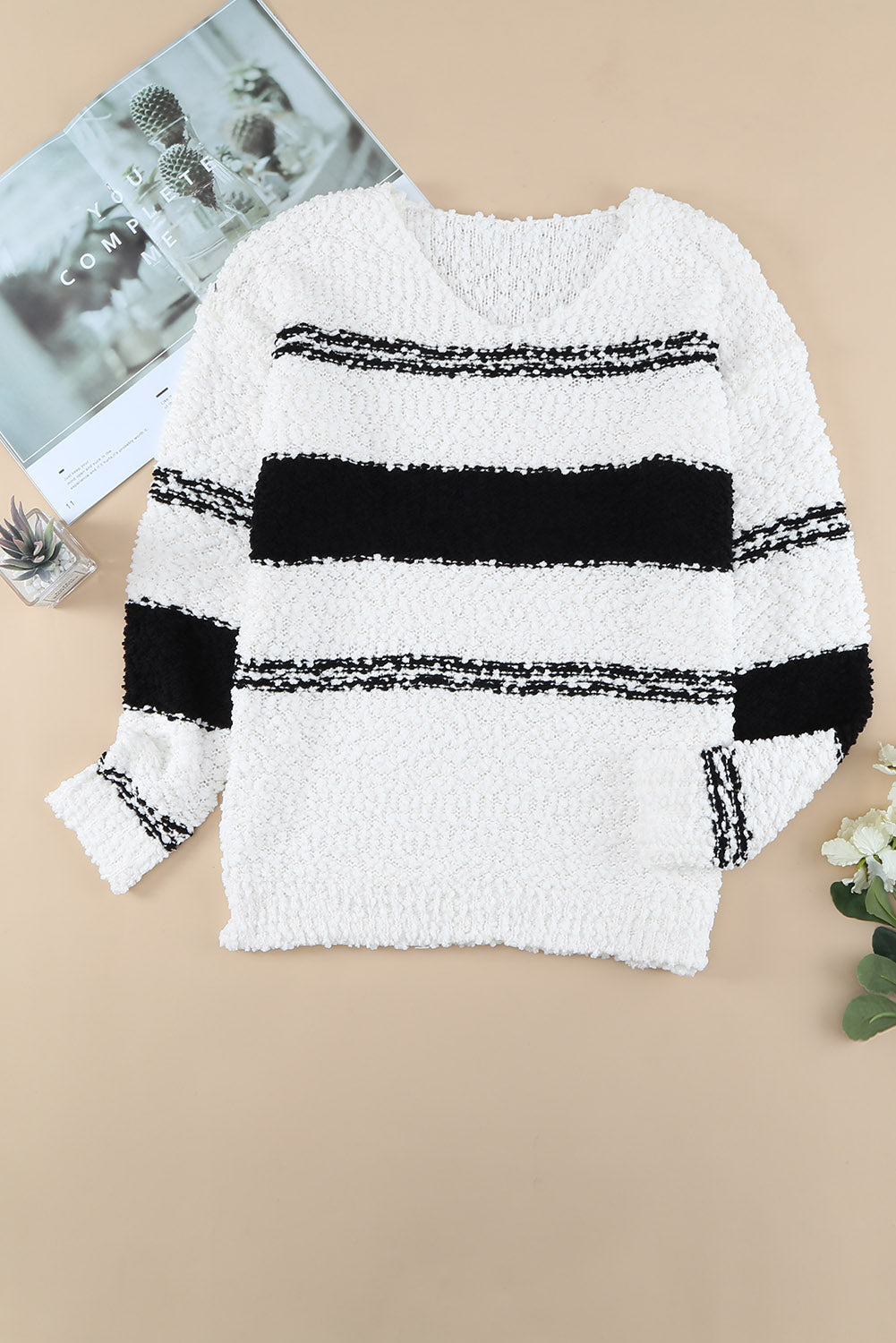 A stylish striped V-neck popcorn knit sweater displayed in a flat lay style, showcasing its casual design and soft texture.