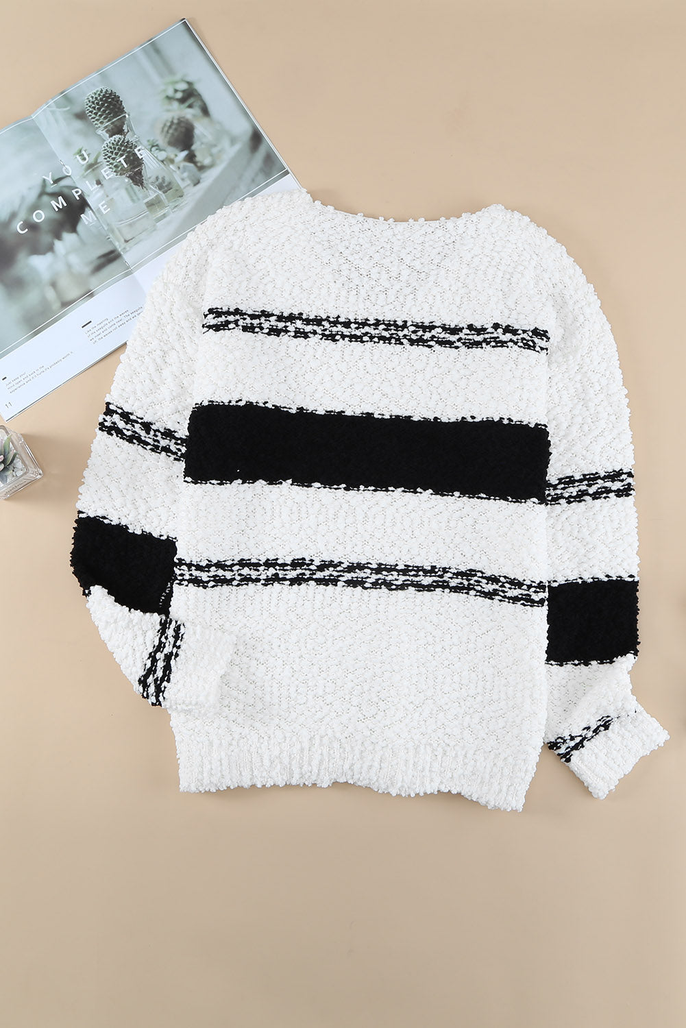 A stylish striped V-neck popcorn knit sweater displayed in a flat lay style, showcasing its casual design and soft texture.