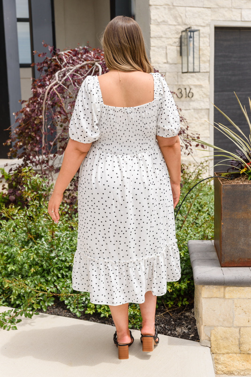 A stylish Sunday Market Dress featuring a square neckline, smocked bodice, slight puff sleeves, and a flowy A-line midi skirt with a ruffle hem.