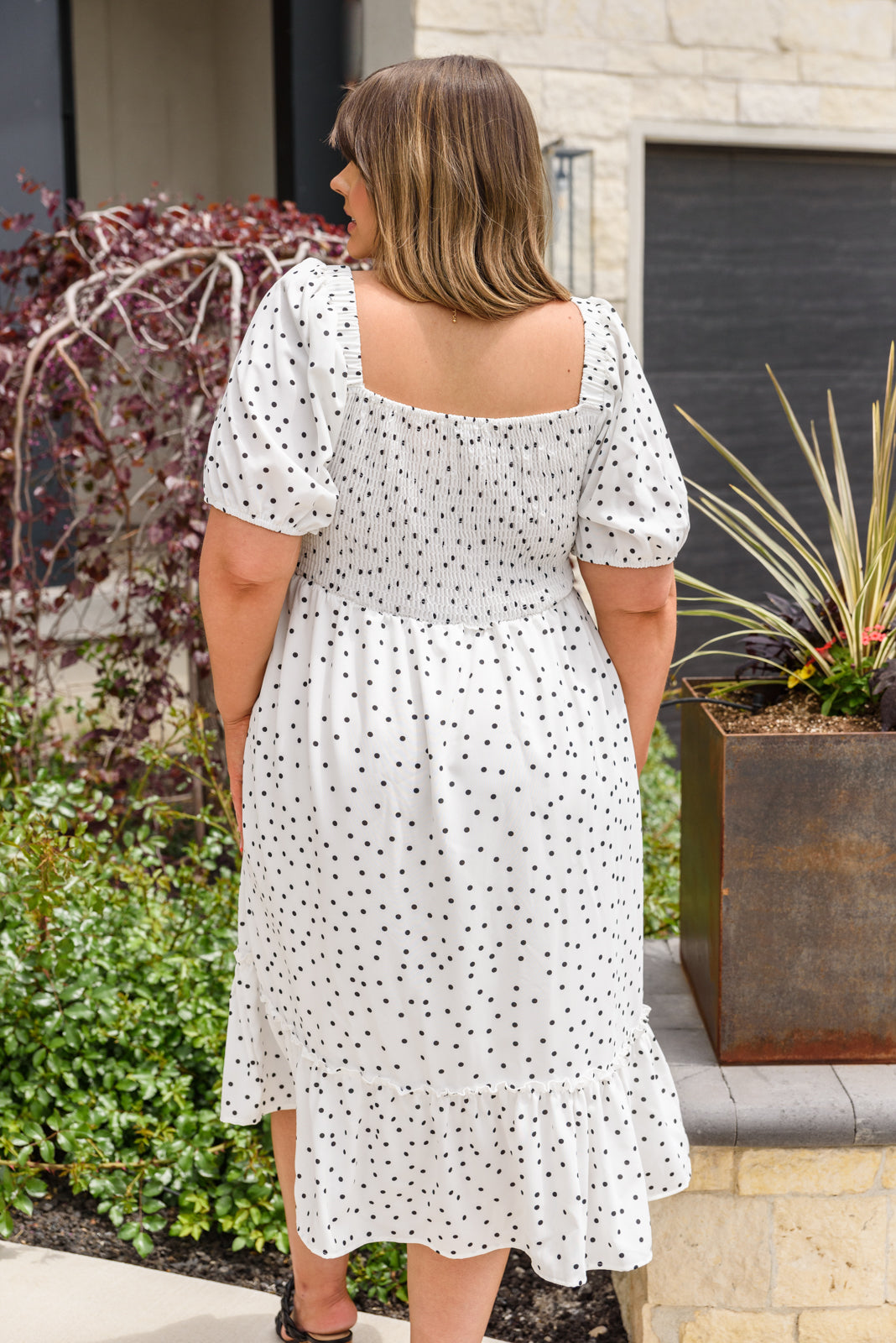 A stylish Sunday Market Dress featuring a square neckline, smocked bodice, slight puff sleeves, and a flowy A-line midi skirt with a ruffle hem.