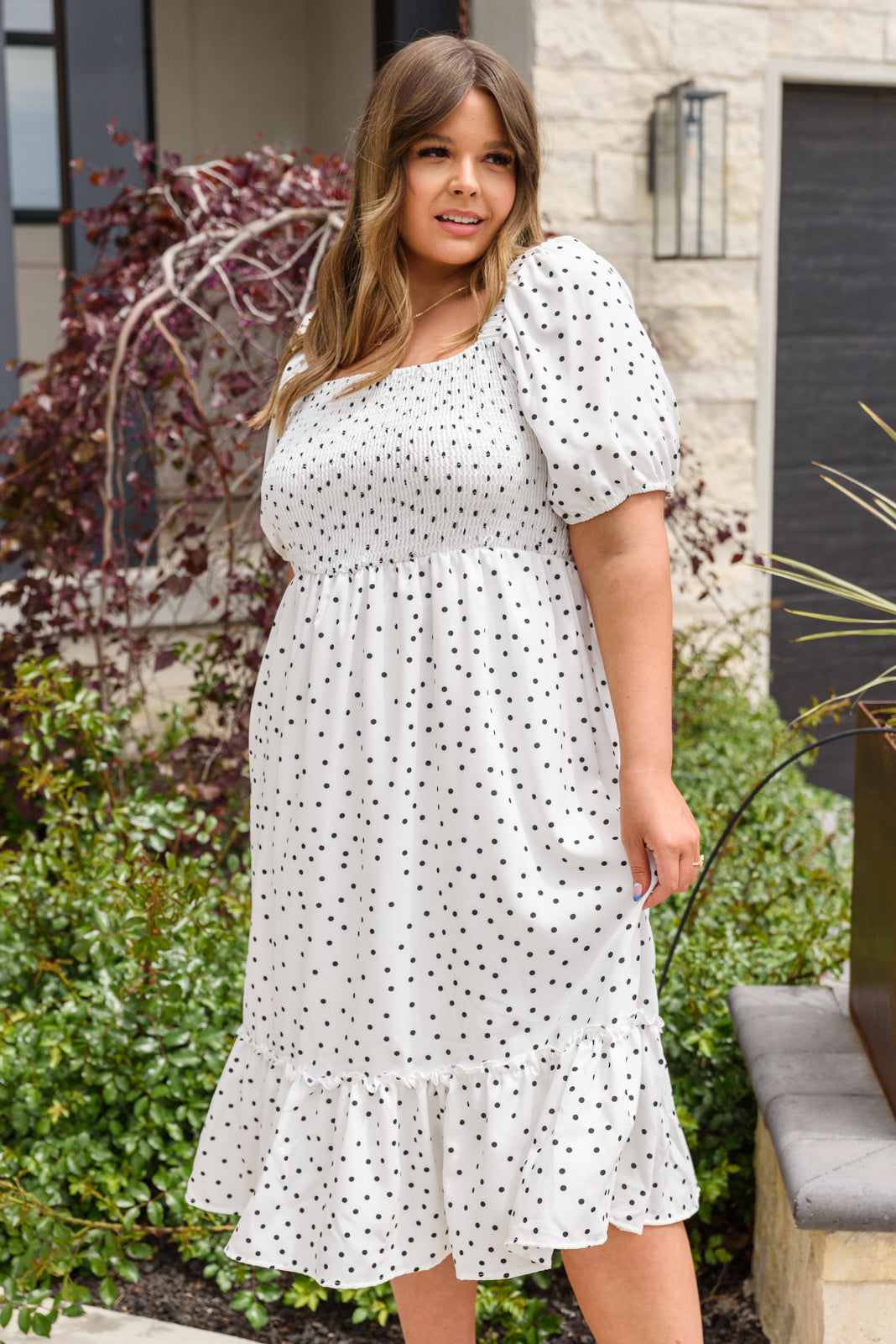 A stylish Sunday Market Dress featuring a square neckline, smocked bodice, slight puff sleeves, and a flowy A-line midi skirt with a ruffle hem.