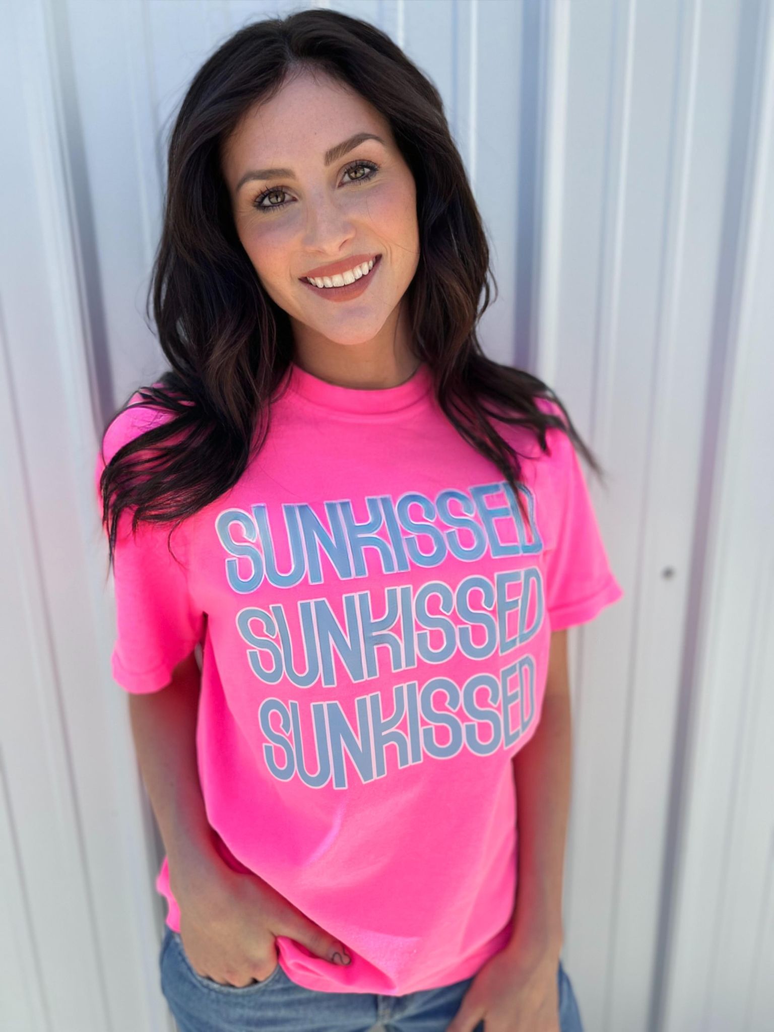 A vibrant Neon Pink Sunkissed Repeating Tee displayed on a hanger, showcasing its soft cotton fabric and unisex design.