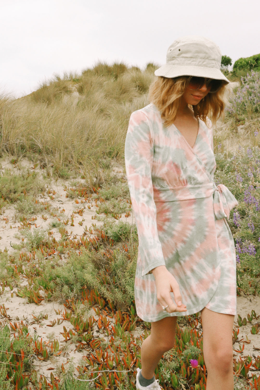 A stylish Sunrise Dress Tie-Dye featuring a saddle pink tie-dye pattern and wrap bell sleeves, perfect for any occasion.