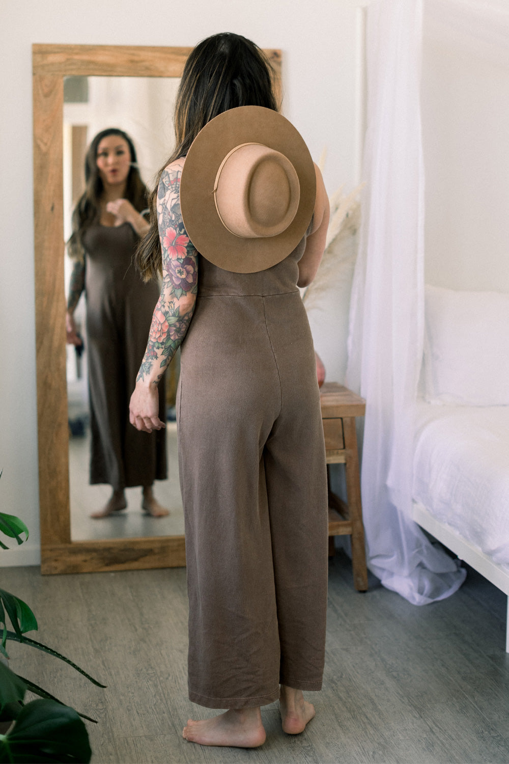 A stylish Sunset Jumpsuit featuring a waist-defining seam, wide legs, and v-neck detailing, available in Washed Black, Sand, and Persimmon colors.