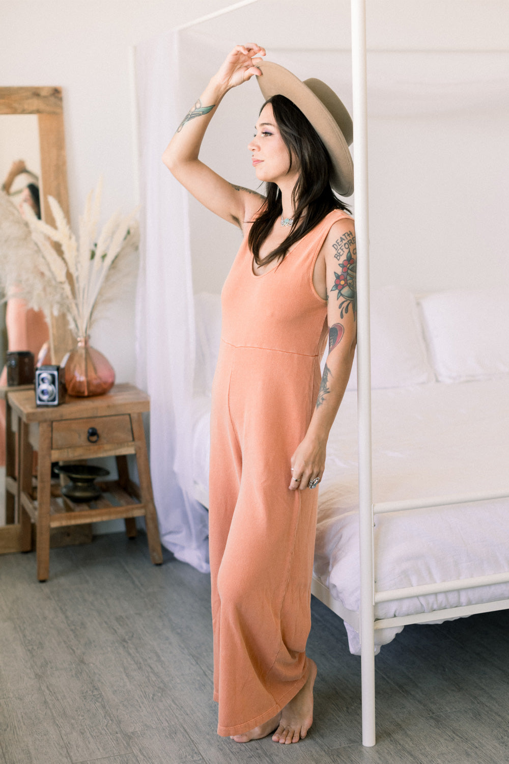 A stylish Sunset Jumpsuit featuring a waist-defining seam, wide legs, and v-neck detailing, available in Washed Black, Sand, and Persimmon colors.