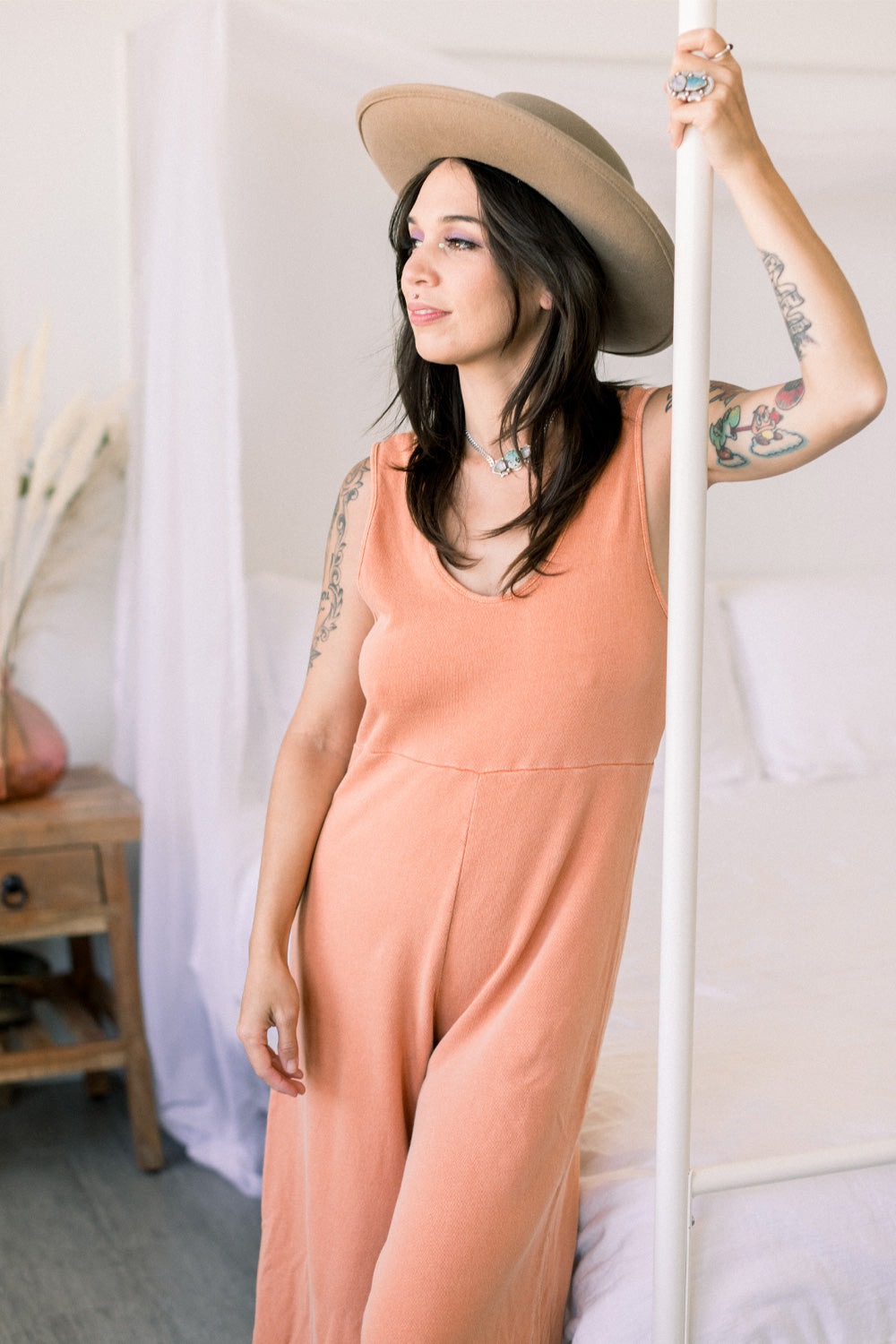 A stylish Sunset Jumpsuit featuring a waist-defining seam, wide legs, and v-neck detailing, available in Washed Black, Sand, and Persimmon colors.