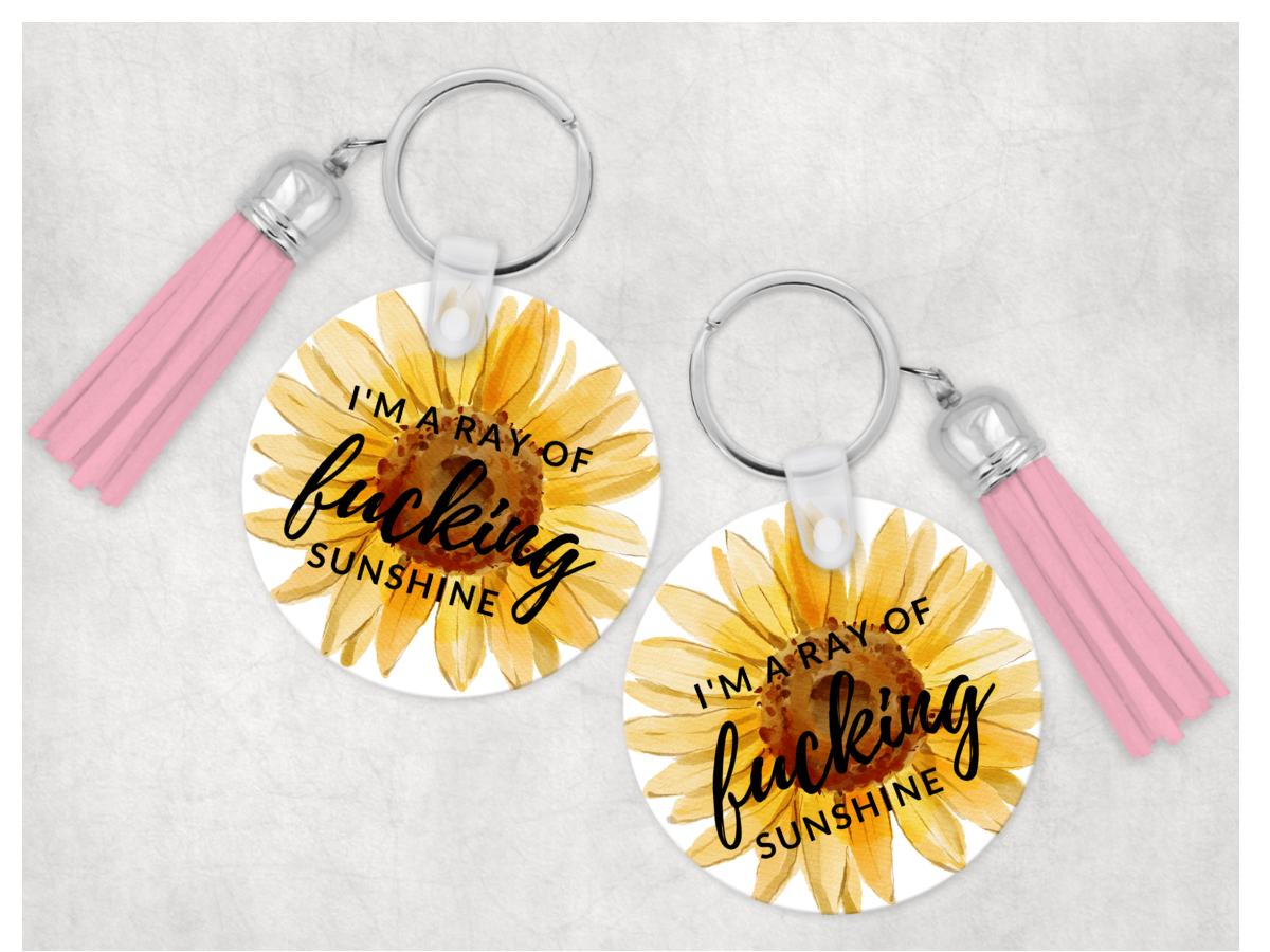 A vibrant keychain featuring the phrase 'Ray of Fucking Sunshine' with a colorful tassel, perfect for adding personality to your keys.