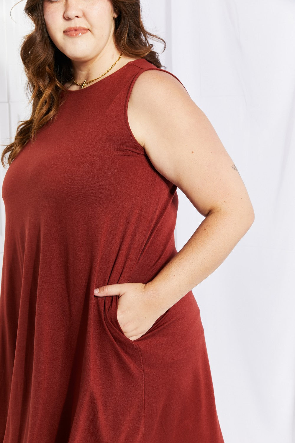 A stylish sleeveless dress in a solid color, featuring a flowy shift cut and pockets, perfect for spring and summer wear.