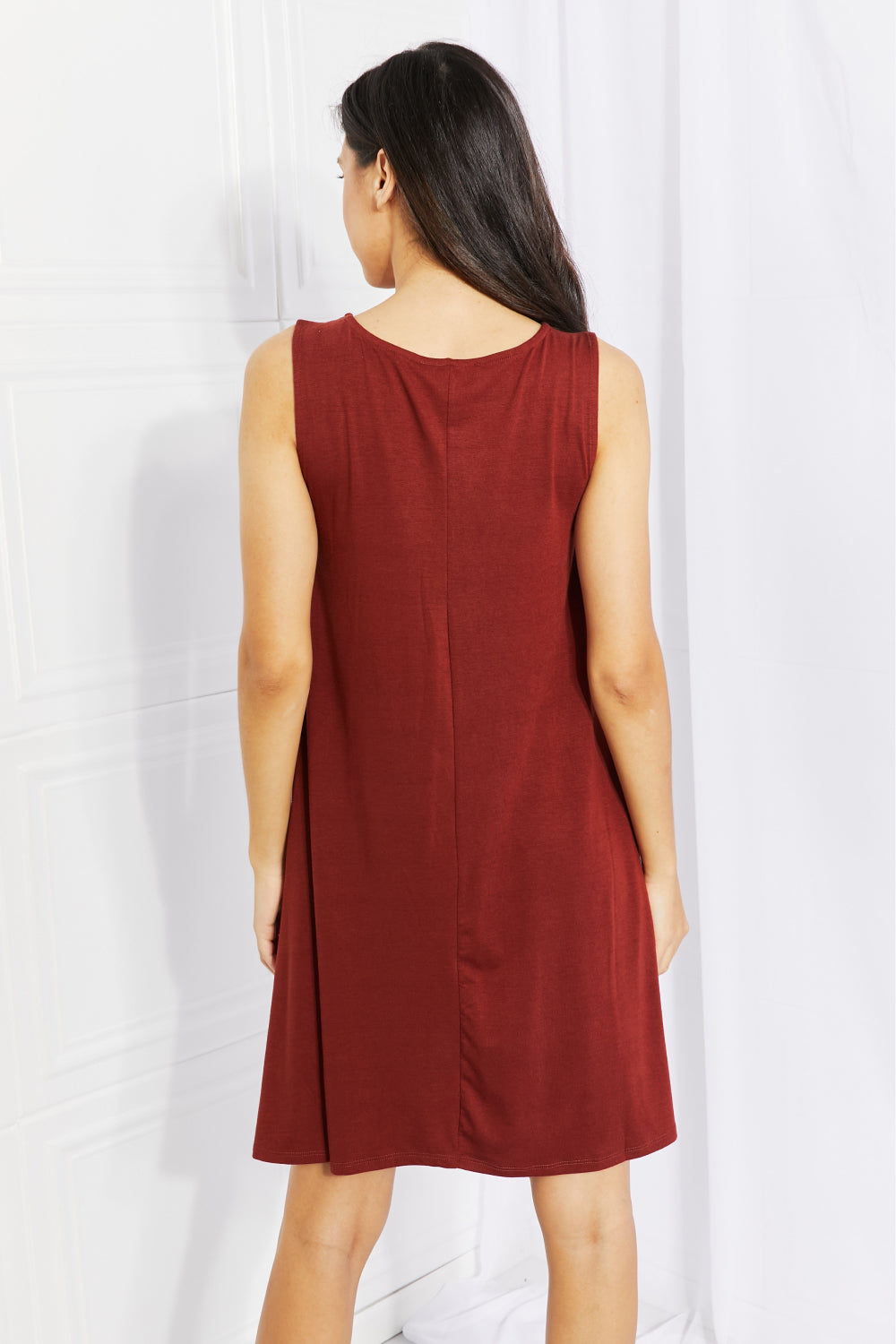 A stylish sleeveless dress in a solid color, featuring a flowy shift cut and pockets, perfect for spring and summer wear.