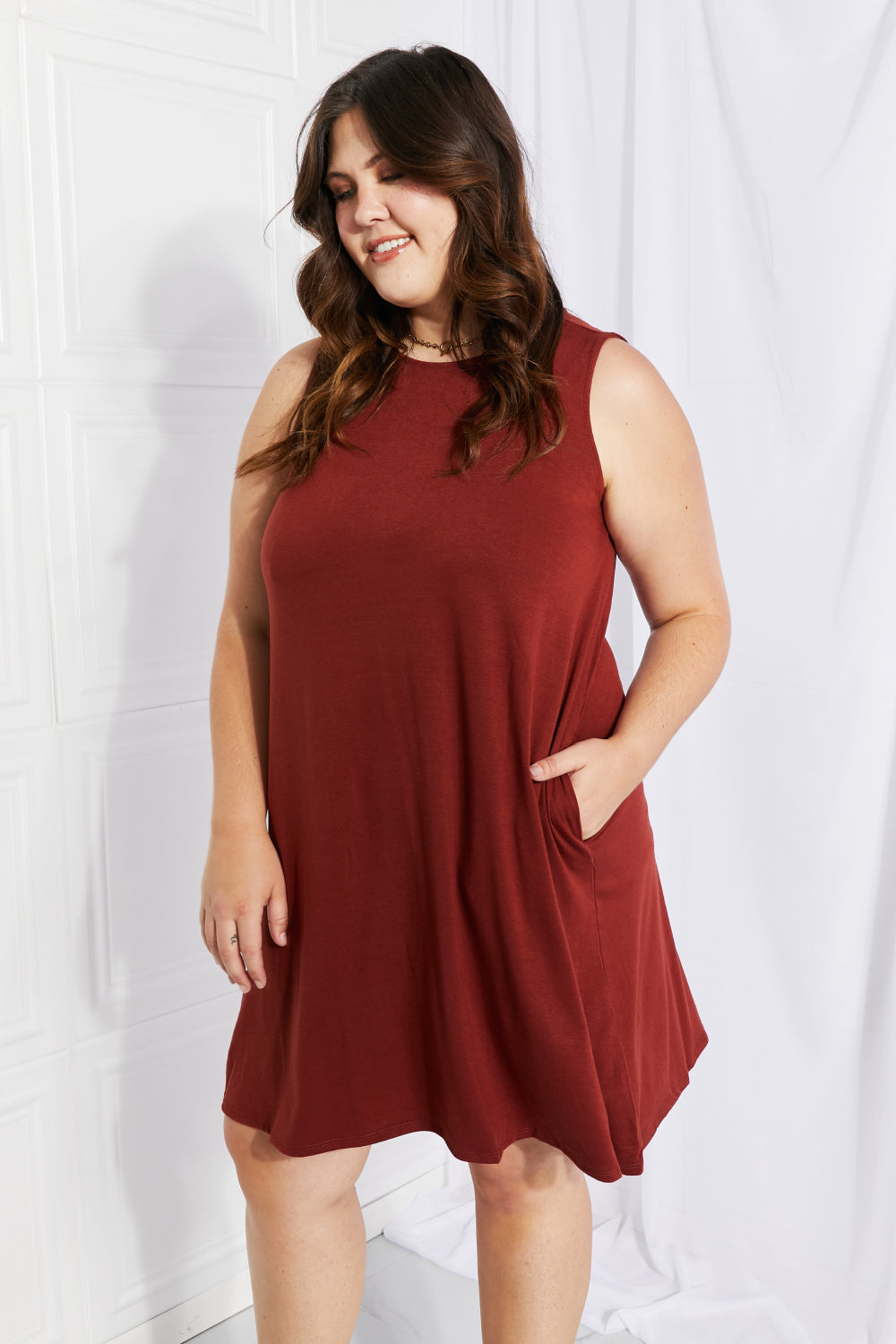 A stylish sleeveless dress in a solid color, featuring a flowy shift cut and pockets, perfect for spring and summer wear.